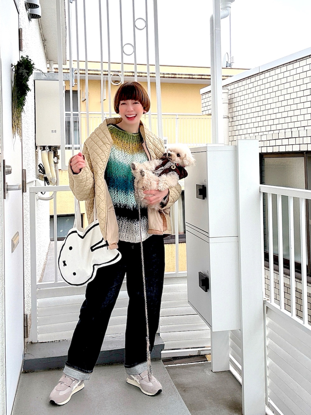 グリーン系のニット/セーター、ベージュ系のダウンジャケット/コート、ブルー系のデニムパンツを着用したレディースの冬コーディネートの2枚目の写真