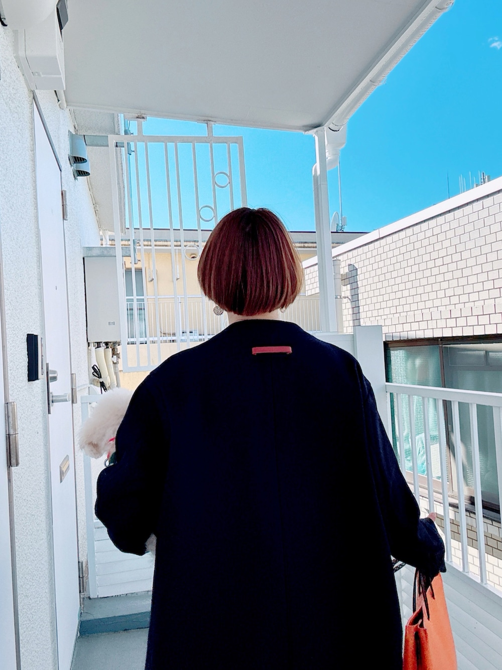 ブルー系のノーカラーコート、ホワイト系のTシャツ/カットソー、グレー系のベストを着用したレディースの秋コーディネートの2枚目の写真