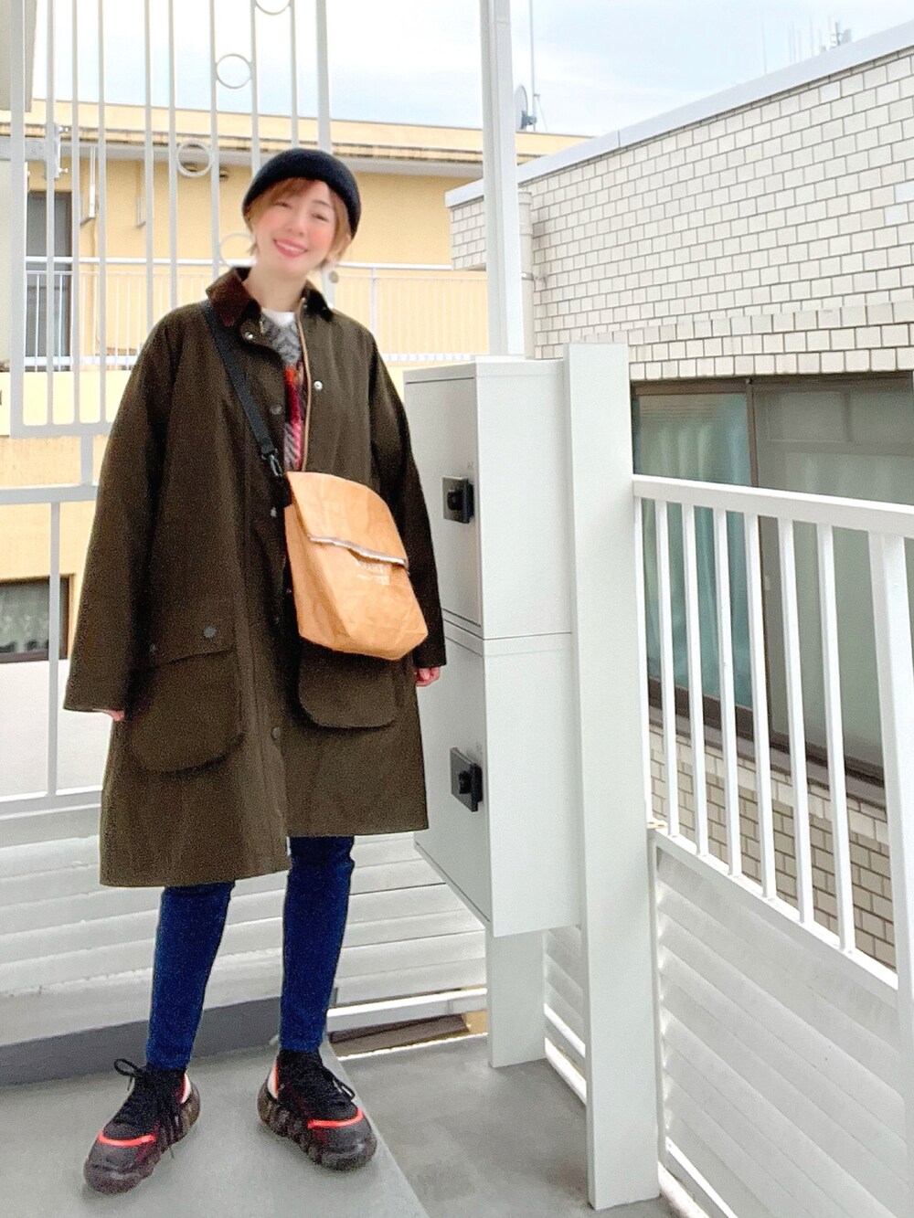 ベージュ系のショルダーバッグ、ブラック系のニット/セーター、ブラック系のスニーカーを着用したレディースの冬コーディネートの2枚目の写真