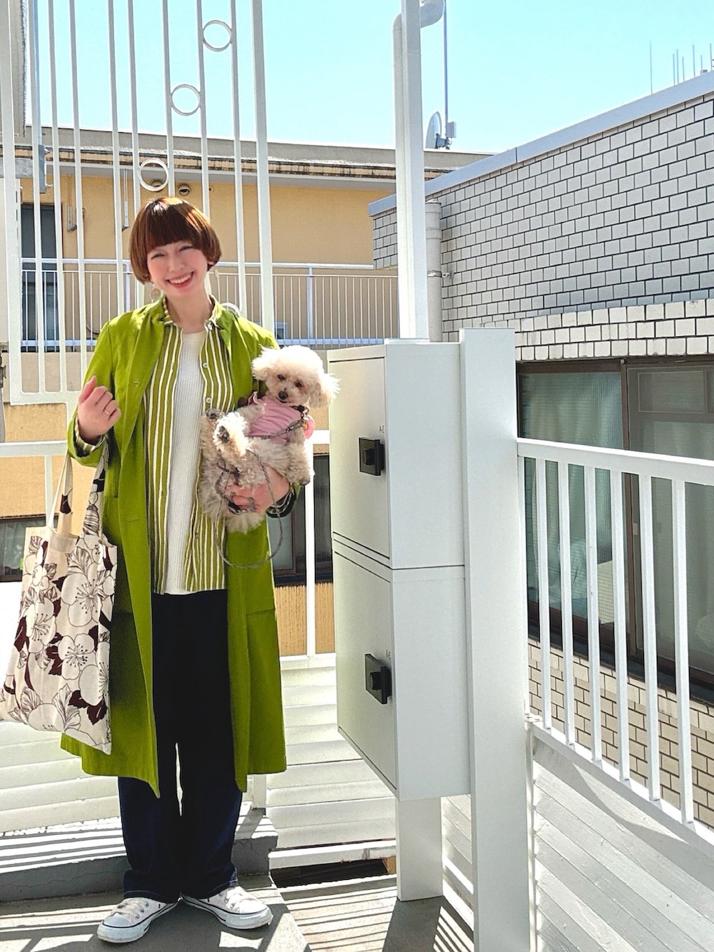 グリーン系のノーカラーコート、グリーン系のシャツ/ブラウス、ブルー系のデニムパンツを着用したレディースの春コーディネートの2枚目の写真