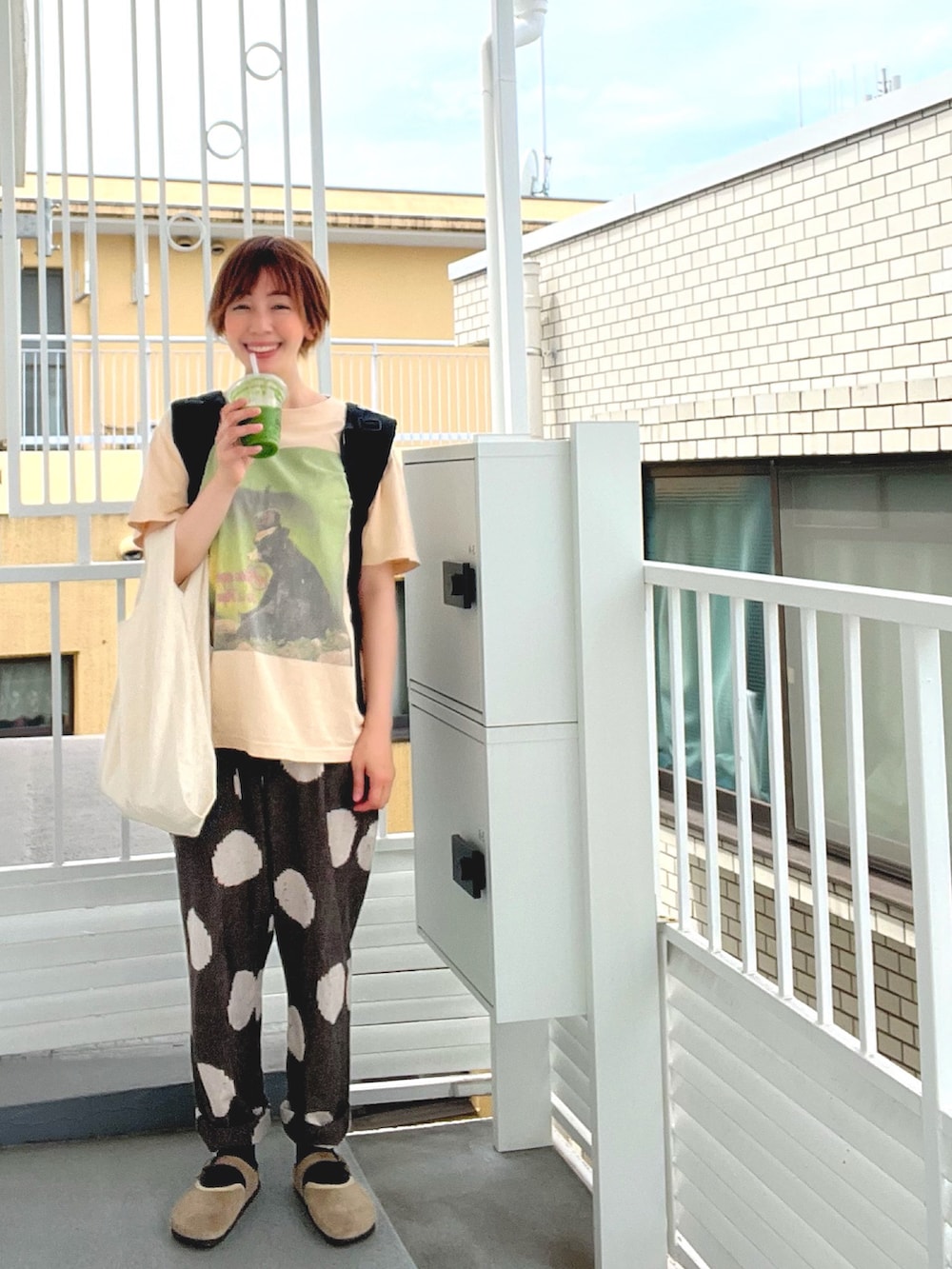 グレー系のTシャツ/カットソー、ブラウン系のかごバッグ、ブルー系のデニムパンツを着用したレディースの夏コーディネートの3枚目の写真