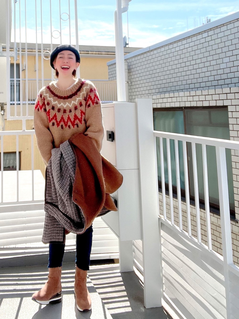 ブラウン系のポンチョ、オレンジ系のショルダーバッグ、ホワイト系のエコバッグ/サブバッグを着用したレディースの冬コーディネートの3枚目の写真