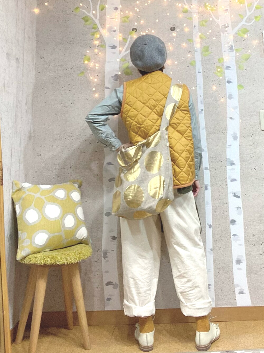 イエロー系のダウンベスト、グレー系のシャツ/ブラウス、ゴールド系のショルダーバッグを着用したレディースの秋コーディネートの2枚目の写真