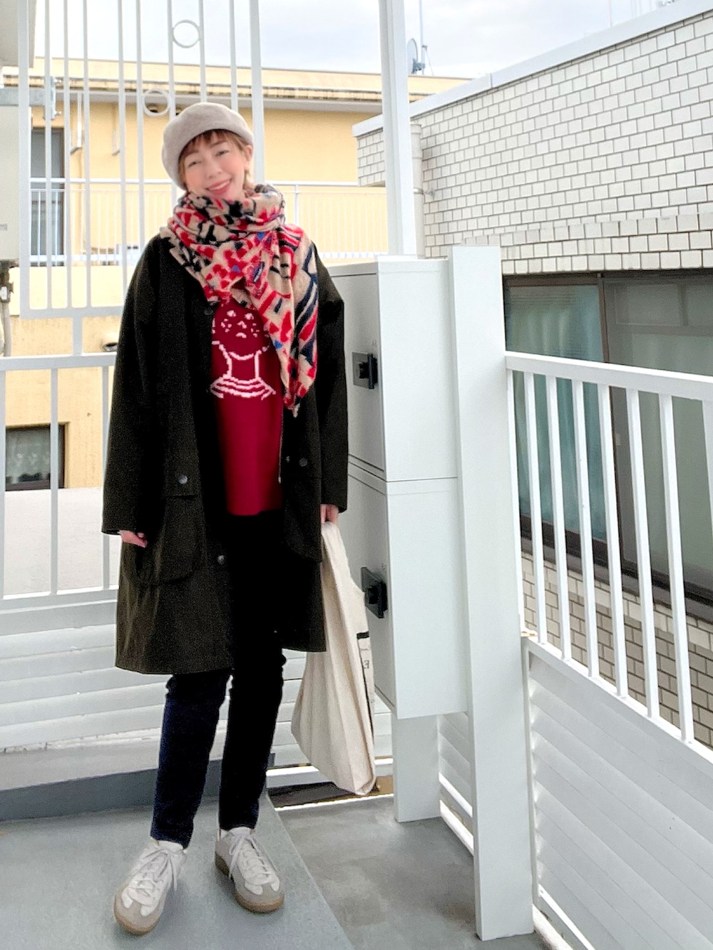 レッド系のニット/セーター、ブルー系のデニムパンツ、グリーン系のステンカラーコートを着用したレディースの冬コーディネートの2枚目の写真