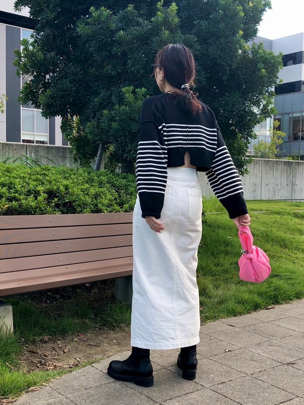 ブラック系のニット/セーター、ホワイト系のスカート、ピンク系のハンドバッグを着用したレディースの秋コーディネートの2枚目の写真