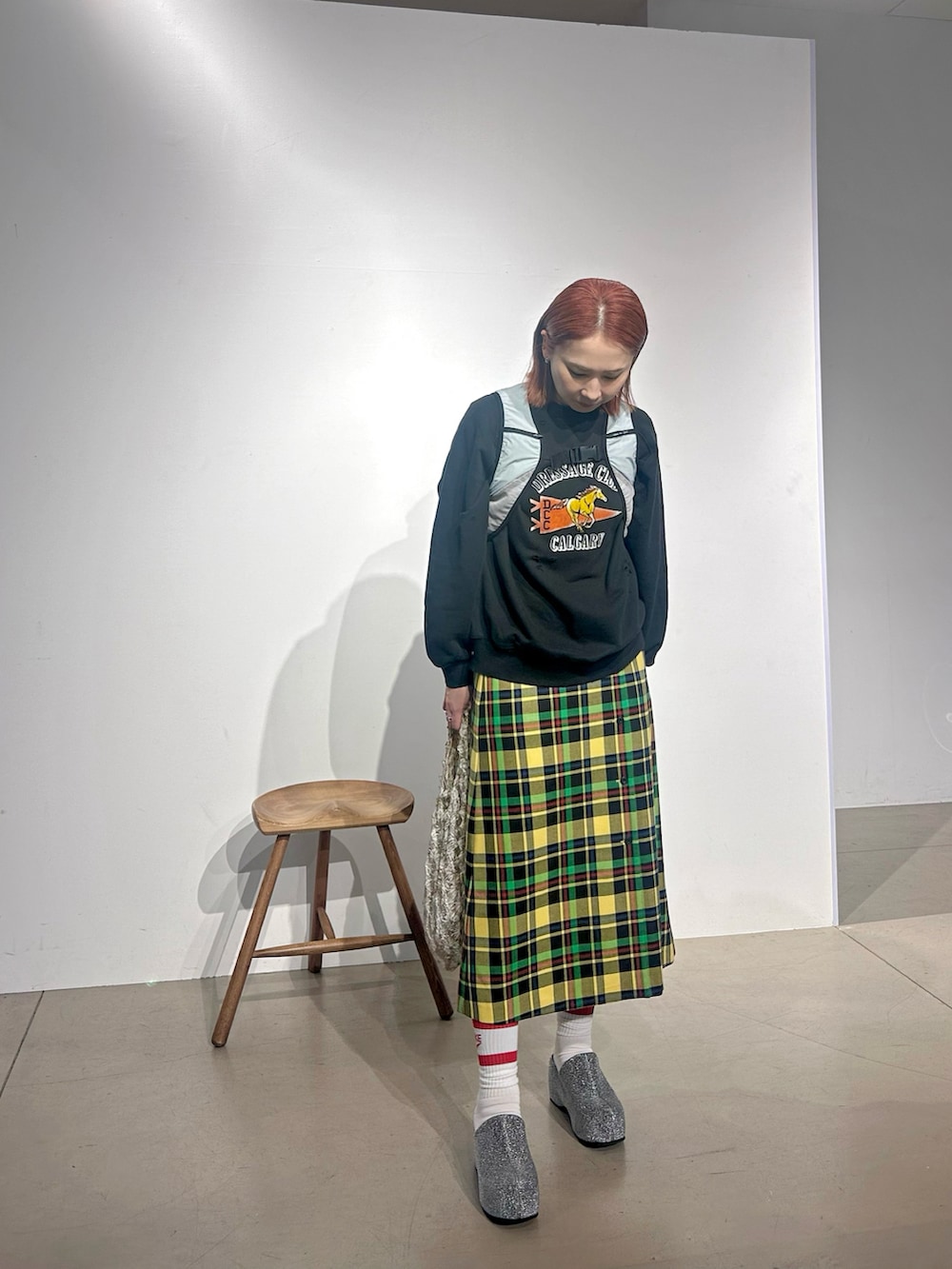 グレー系のスウェット、ブルー系のベスト、イエロー系のスカートを着用したレディースの秋コーディネートの2枚目の写真