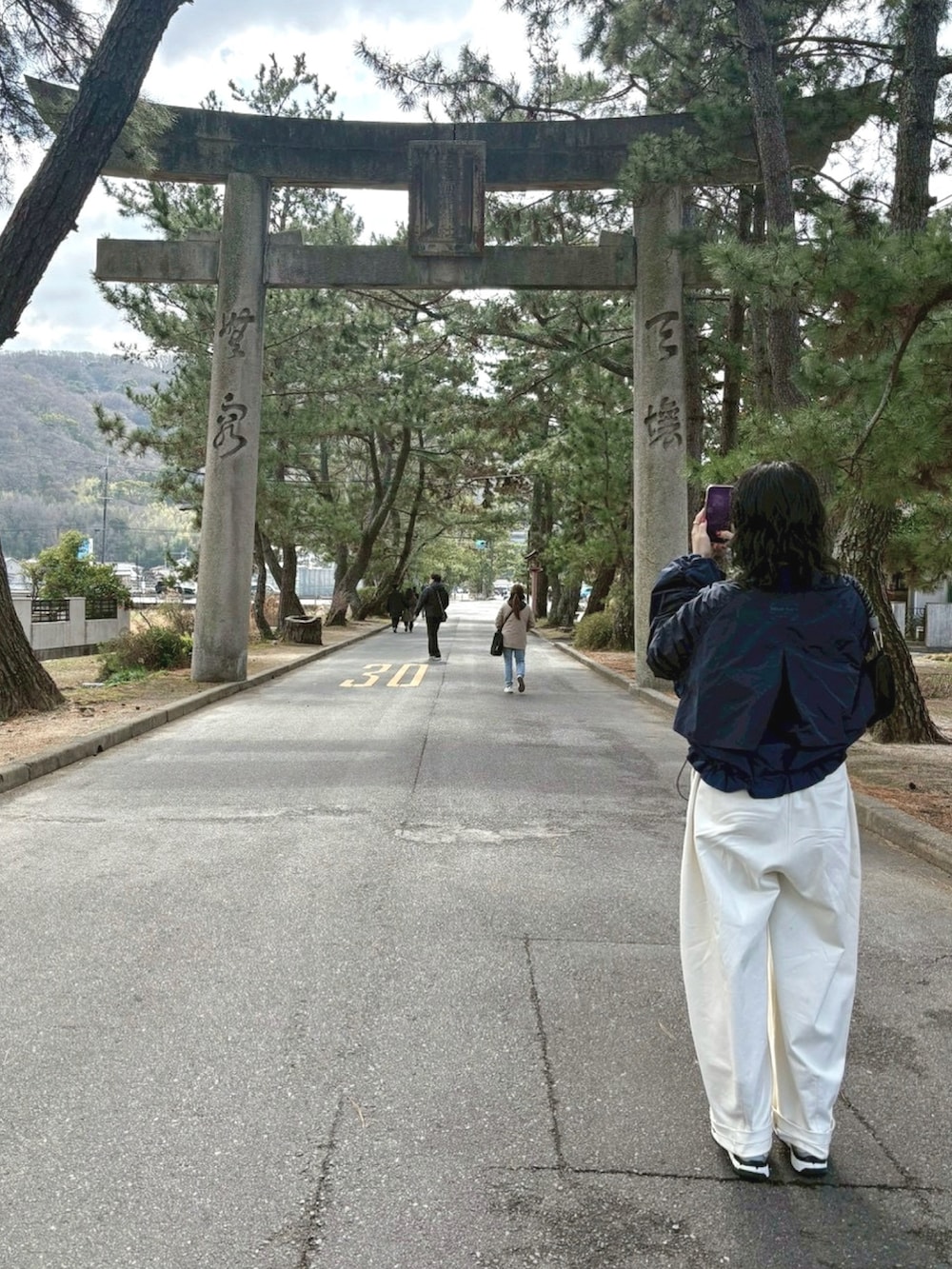 ブラック系のショルダーバッグ、ブラック系のTシャツ/カットソー、ホワイト系のスウェットパンツを着用したレディースの春コーディネートの2枚目の写真