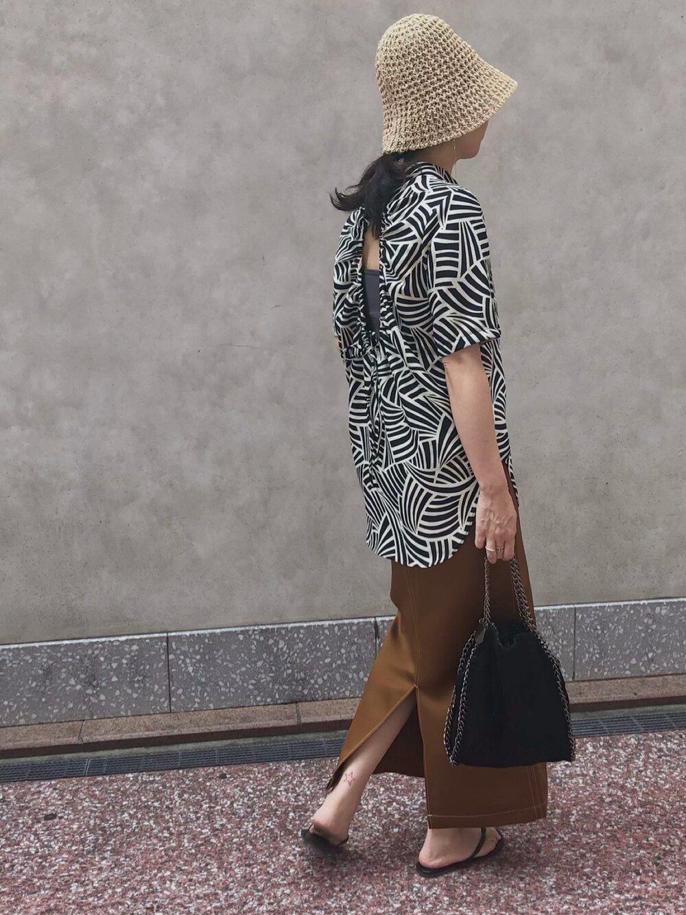 ブラック系のシャツ/ブラウス、ベージュ系のスカート、ブラック系のハンドバッグを着用したレディースの夏コーディネートの2枚目の写真