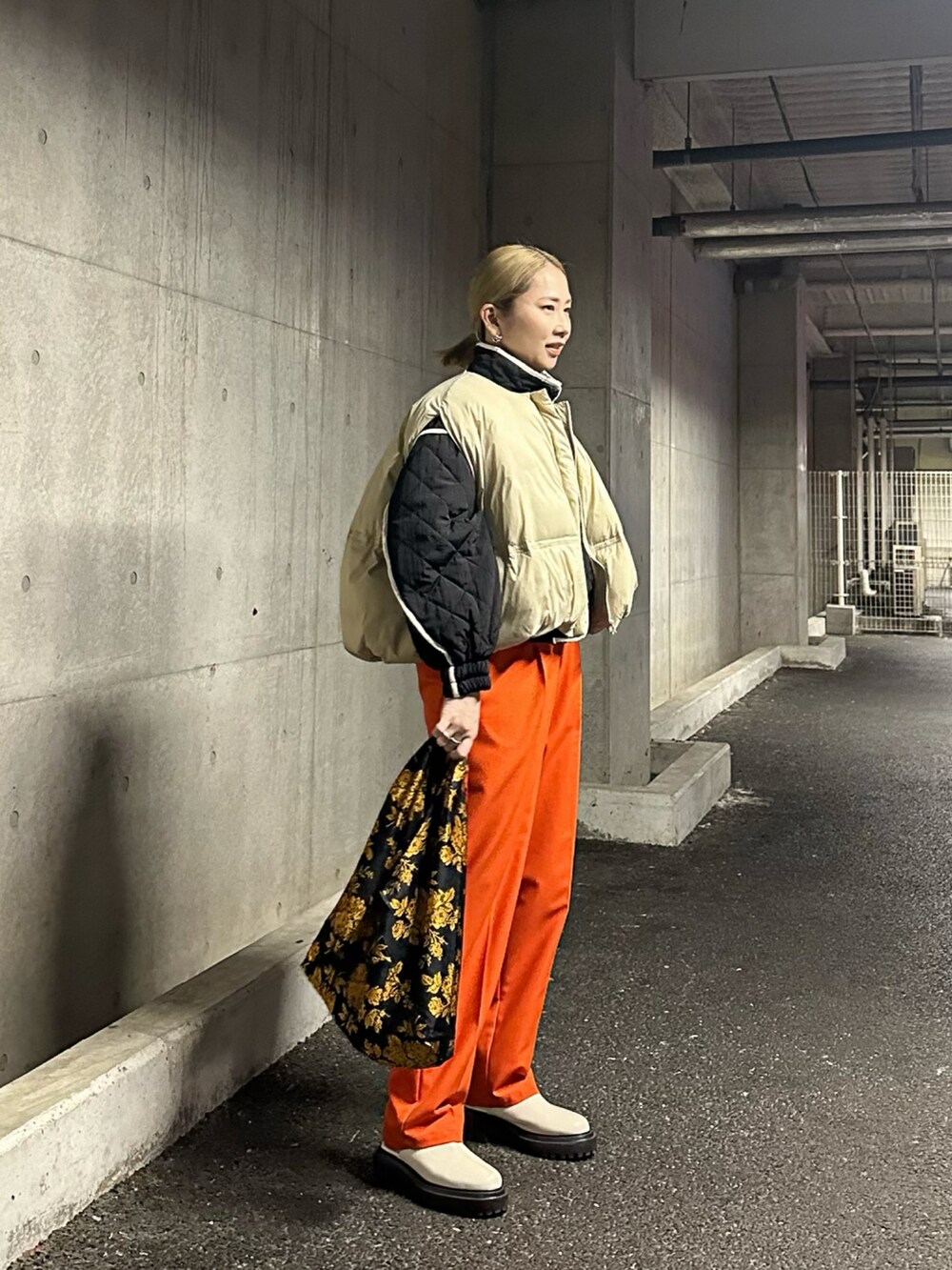 ブラック系のブルゾン、ホワイト系のダウンベスト、オレンジ系のその他パンツを着用したレディースの冬コーディネートの2枚目の写真