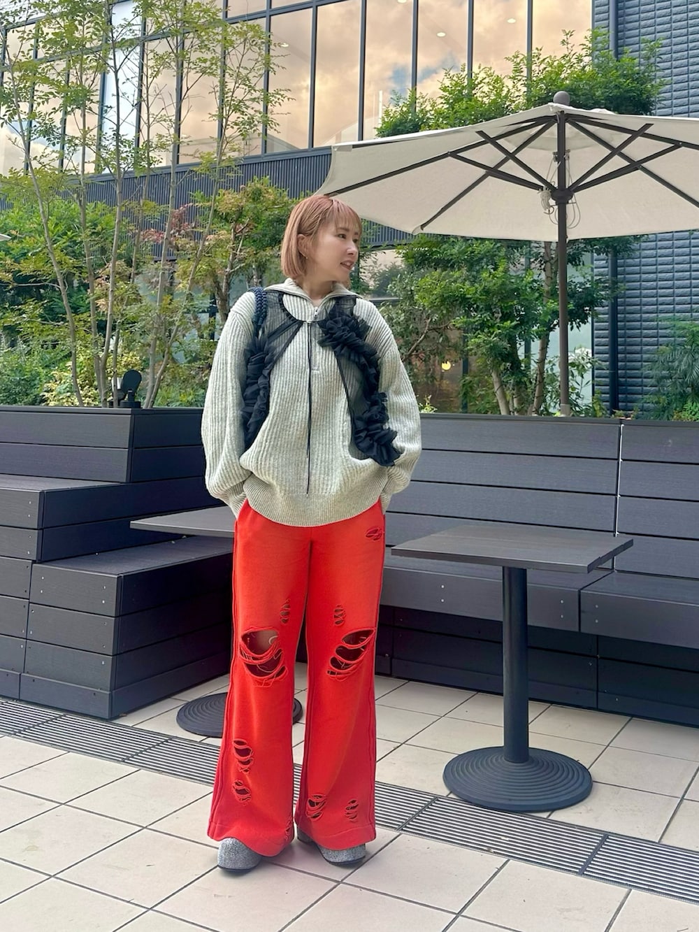 グレー系のニット/セーター、ブラック系のトップス、レッド系のスウェットパンツを着用したレディースの冬コーディネートの2枚目の写真