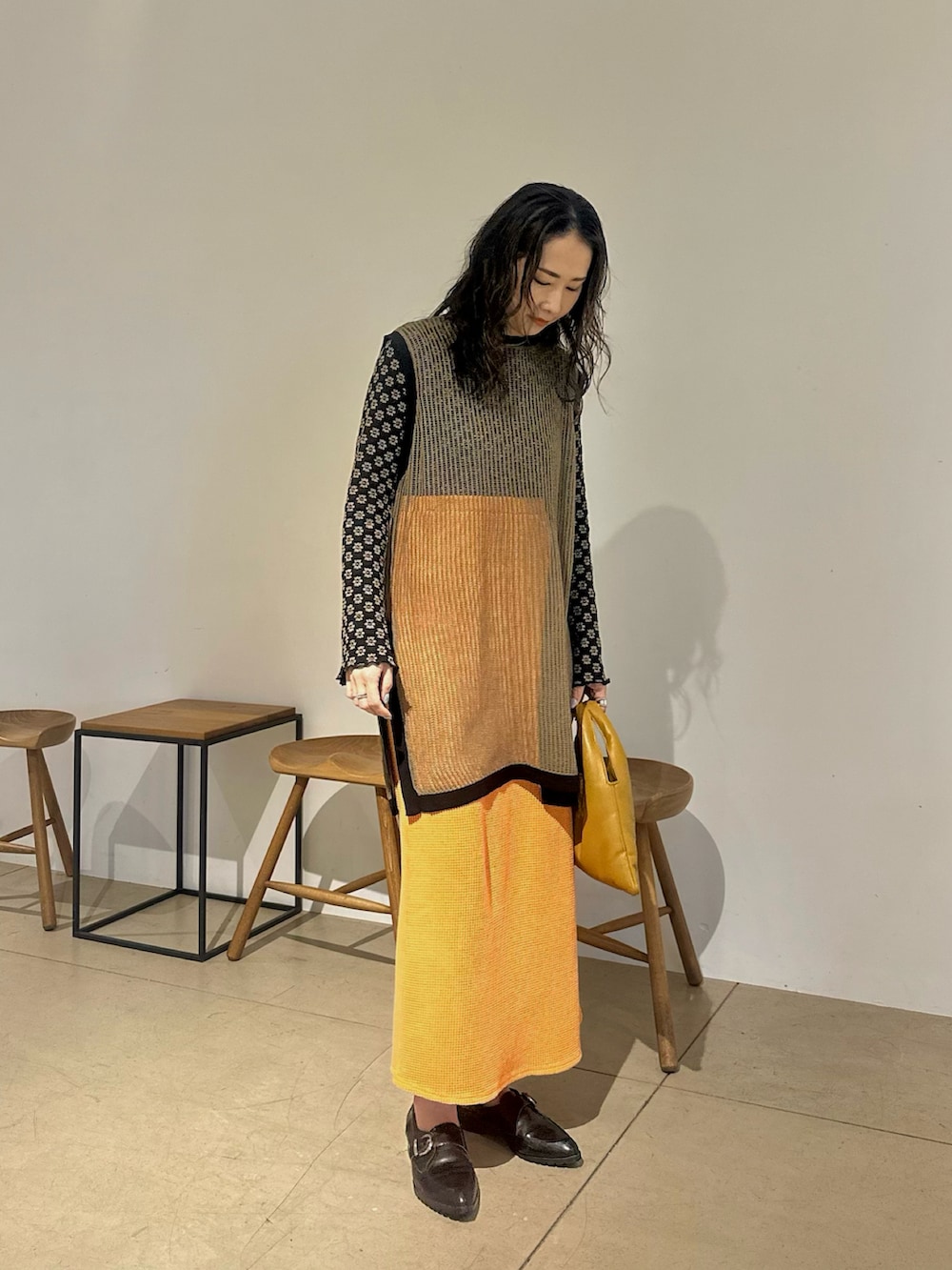 グリーン系のニット/セーター、グレー系のTシャツ/カットソー、オレンジ系のスカートを着用したレディースの春コーディネートの2枚目の写真