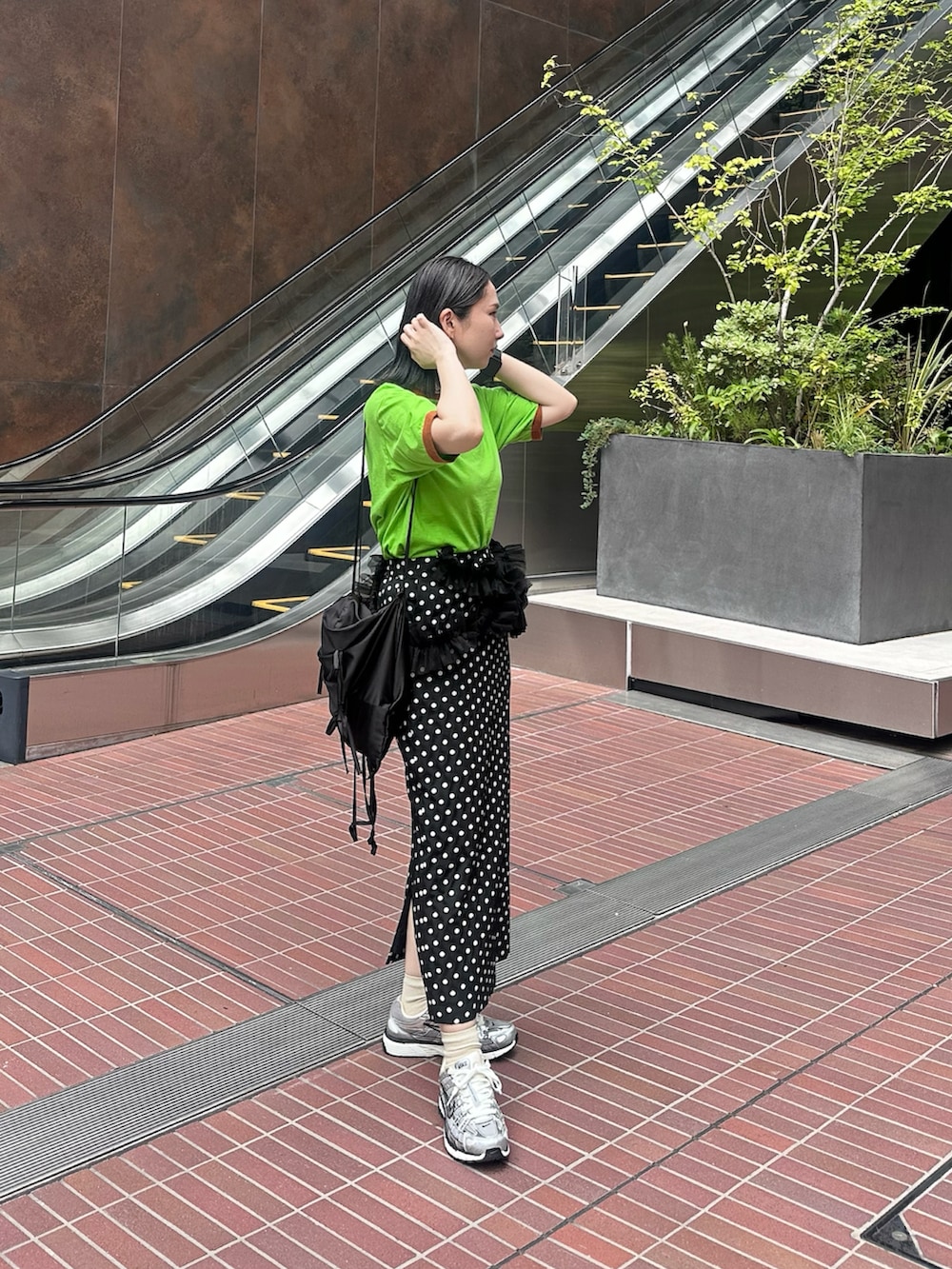 グリーン系のTシャツ/カットソー、ブラック系のスカート、ブラック系のバックパック/リュックを着用したレディースの夏コーディネートの2枚目の写真