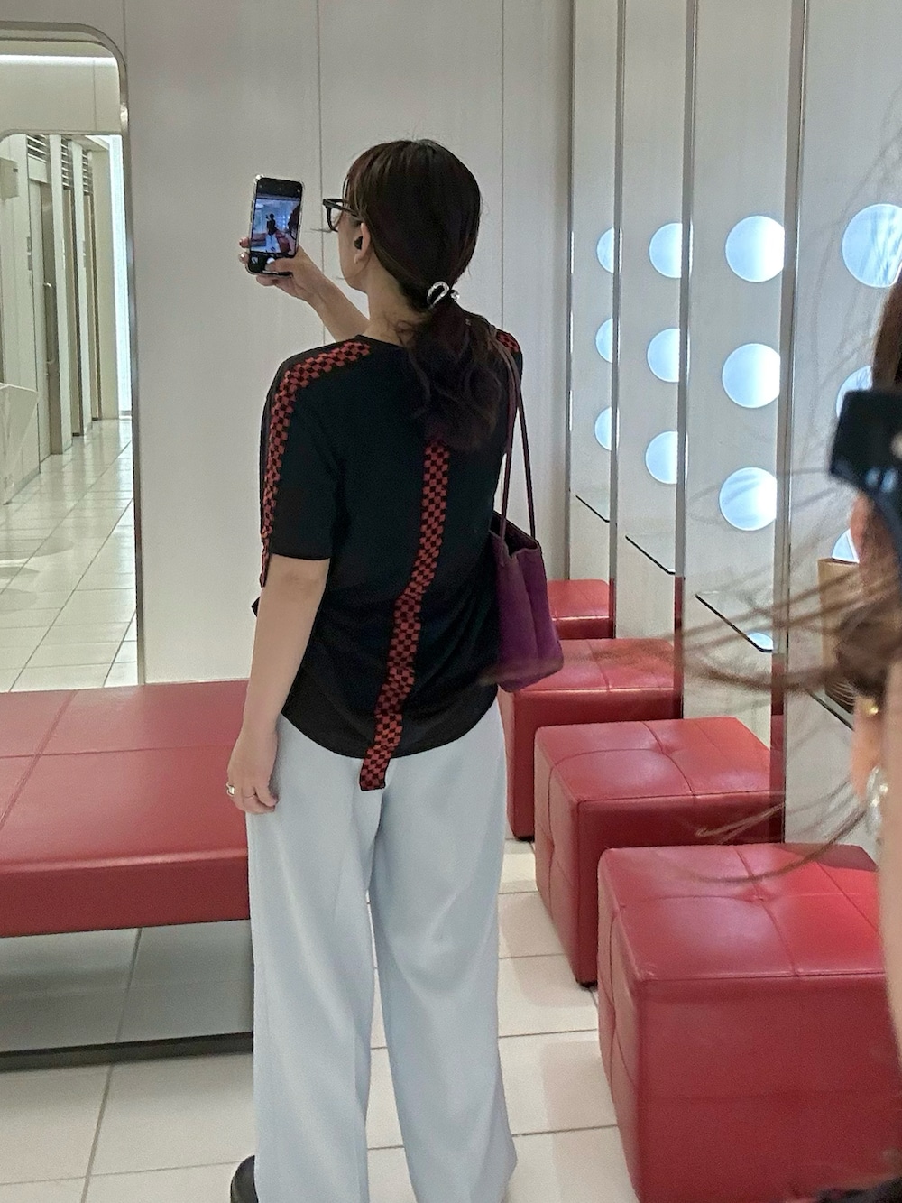 ブラック系のTシャツ/カットソー、ブルー系のスラックス、パープル系のトートバッグを着用したレディースの秋コーディネートの2枚目の写真