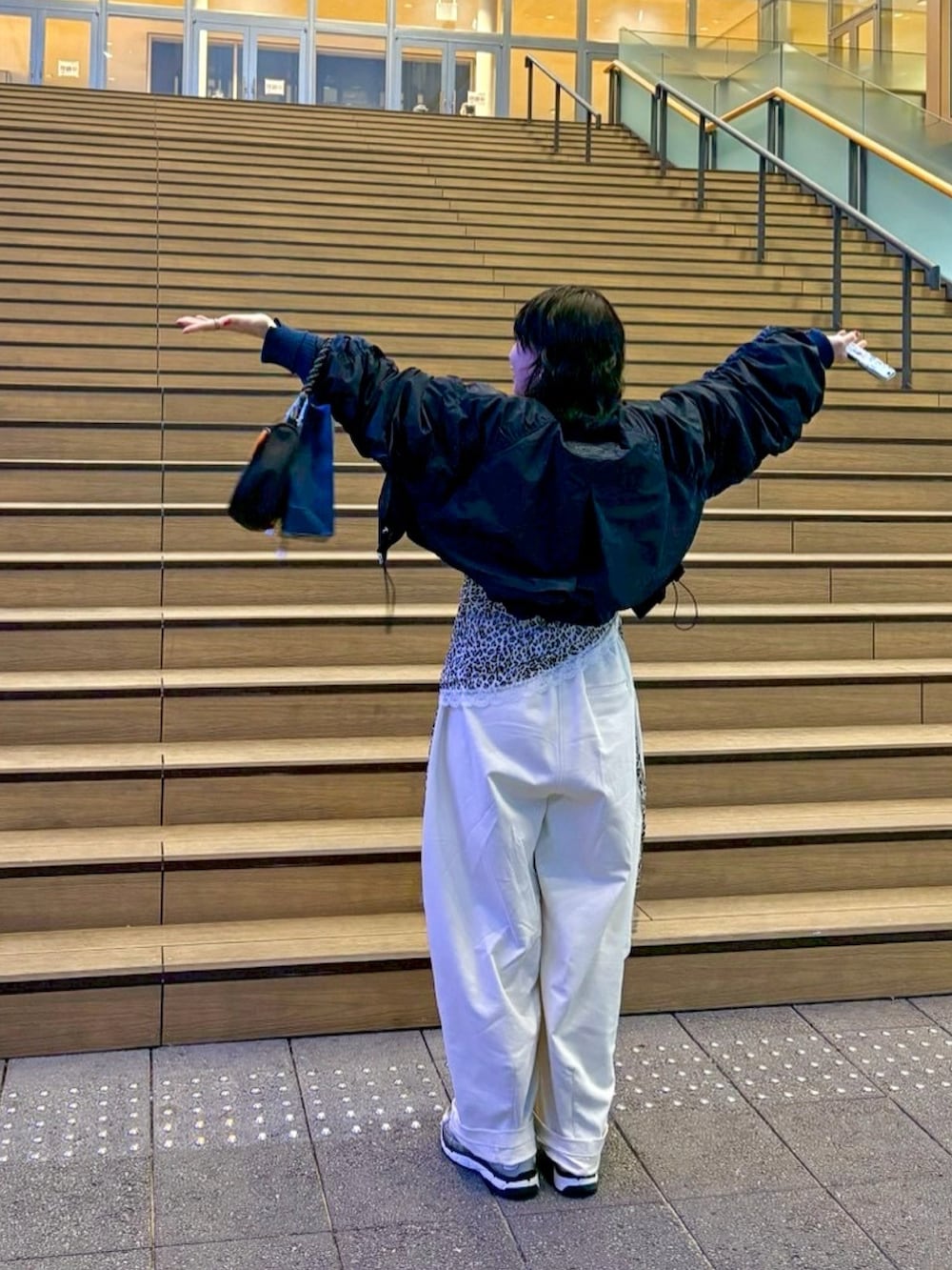 ブラック系のショルダーバッグ、ホワイト系のスウェットパンツ、グリーン系のニット/セーターを着用したレディースの春コーディネートの2枚目の写真