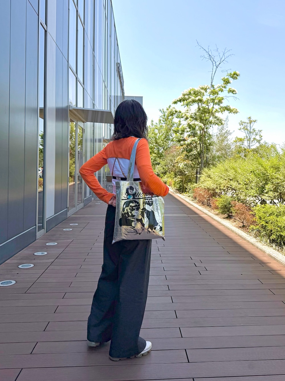 ブラック系のその他パンツ、ホワイト系のTシャツ/カットソー、オレンジ系のニット/セーターを着用したレディースの春コーディネートの2枚目の写真
