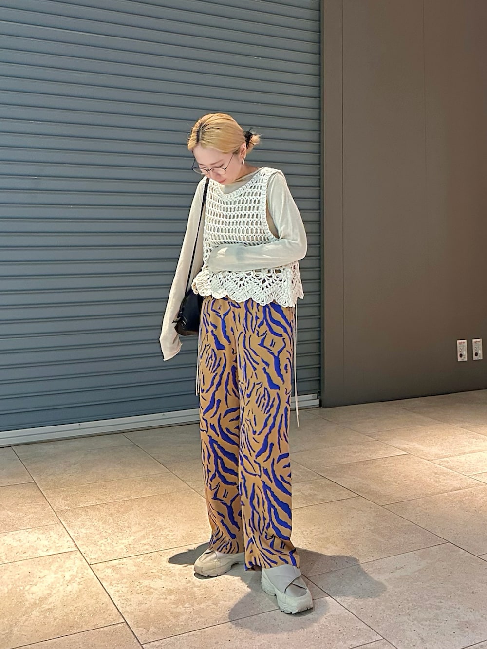 ホワイト系のベスト、オレンジ系のその他パンツ、ブラック系のバックパック/リュックを着用したレディースの春コーディネートの2枚目の写真