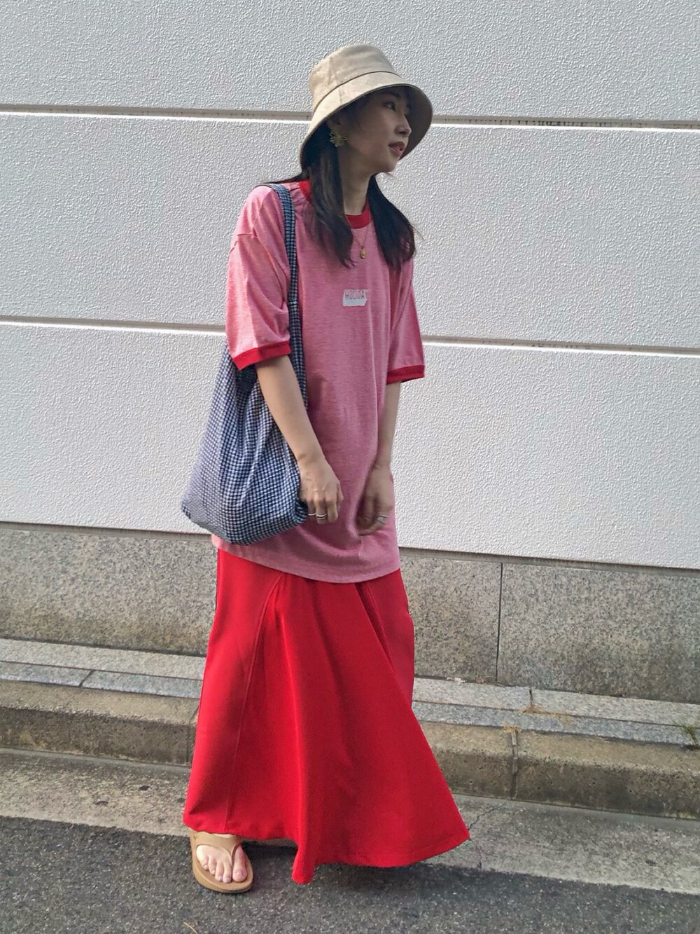 レッド系のTシャツ/カットソー、レッド系のスカート、ブラック系のトートバッグを着用したレディースの夏コーディネートの2枚目の写真