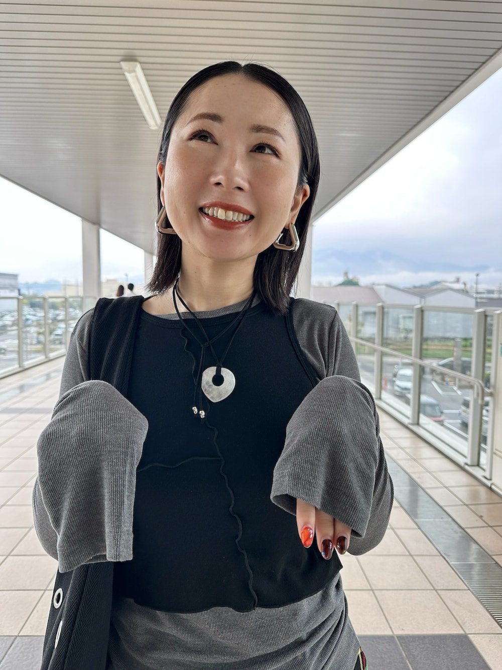 グレー系のTシャツ/カットソー、ブラック系のブーツ、ブラック系のトートバッグを着用したレディースの秋コーディネートの2枚目の写真