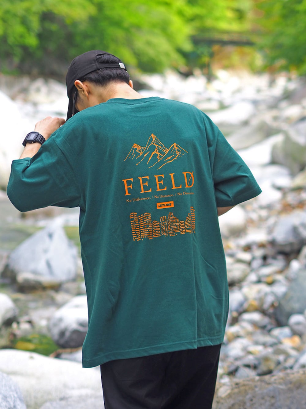 グリーン系のTシャツ/カットソー、ベージュ系のスニーカー、ブラック系のキャップを着用したメンズの春コーディネートの2枚目の写真