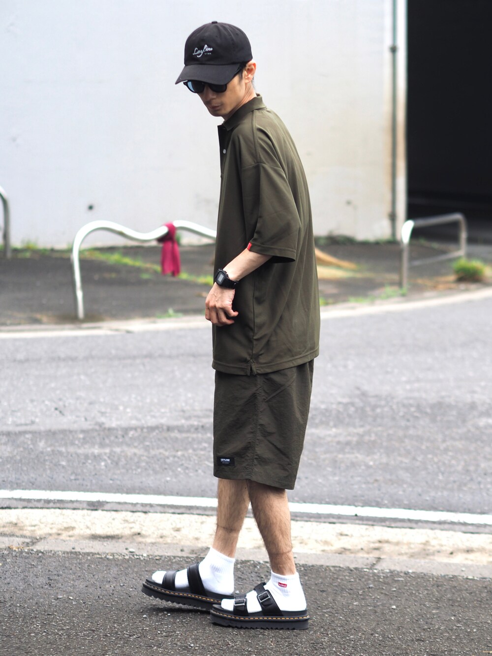 グリーン系のポロシャツ、ブラック系のその他パンツ、ブラック系のサンダルを着用したメンズの春コーディネートの2枚目の写真