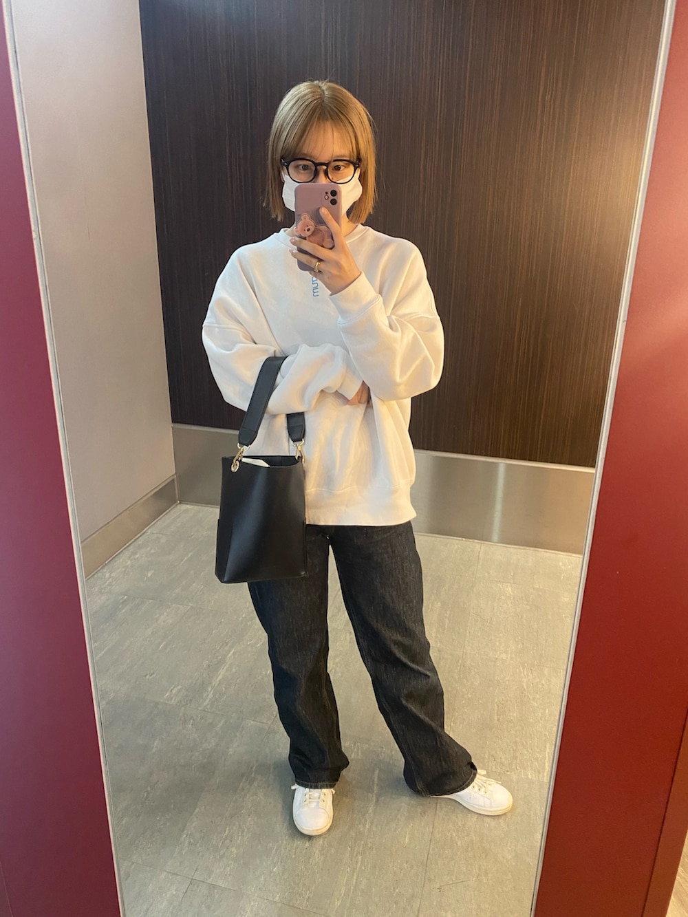 ブラック系のショルダーバッグ、ホワイト系のスウェット、ブルー系のデニムパンツを着用したレディースの春コーディネートの2枚目の写真