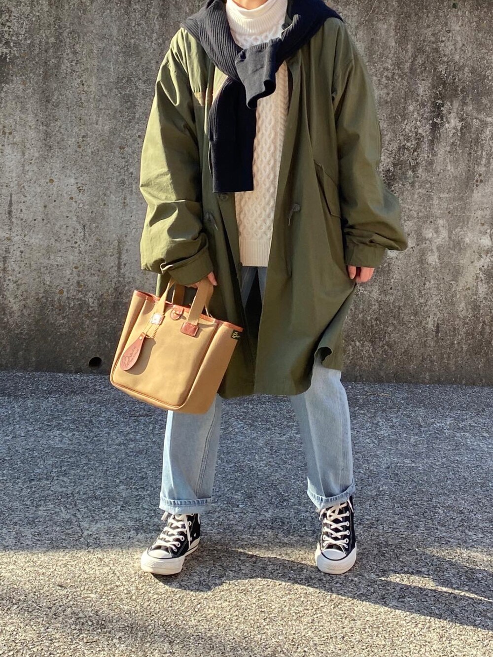 グリーン系のミリタリージャケット、ブルー系のデニムパンツ、グリーン系のトートバッグを着用したレディースの冬コーディネートの2枚目の写真