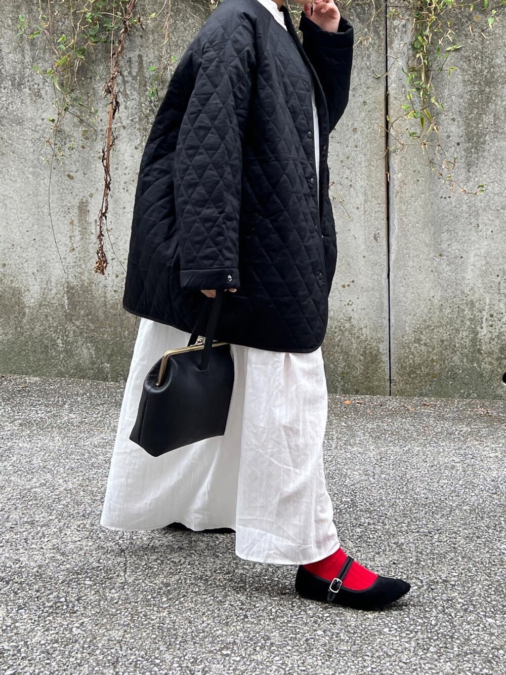 ブラック系のノーカラーコート、ホワイト系のワンピースを着用したレディースの秋コーディネートの2枚目の写真