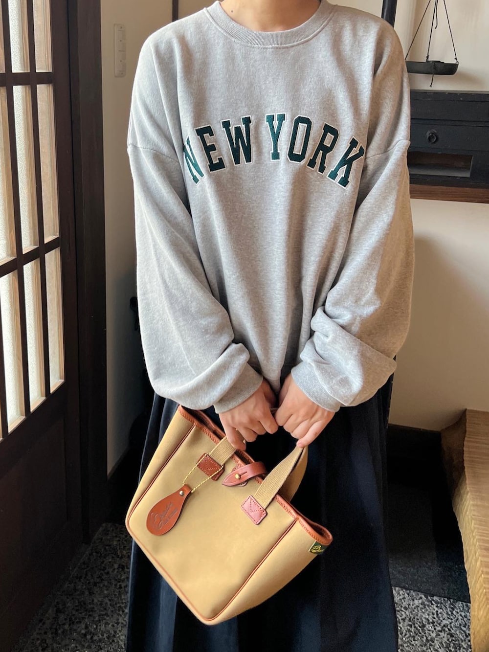 グリーン系のトートバッグを着用したレディースの秋コーディネートの2枚目の写真