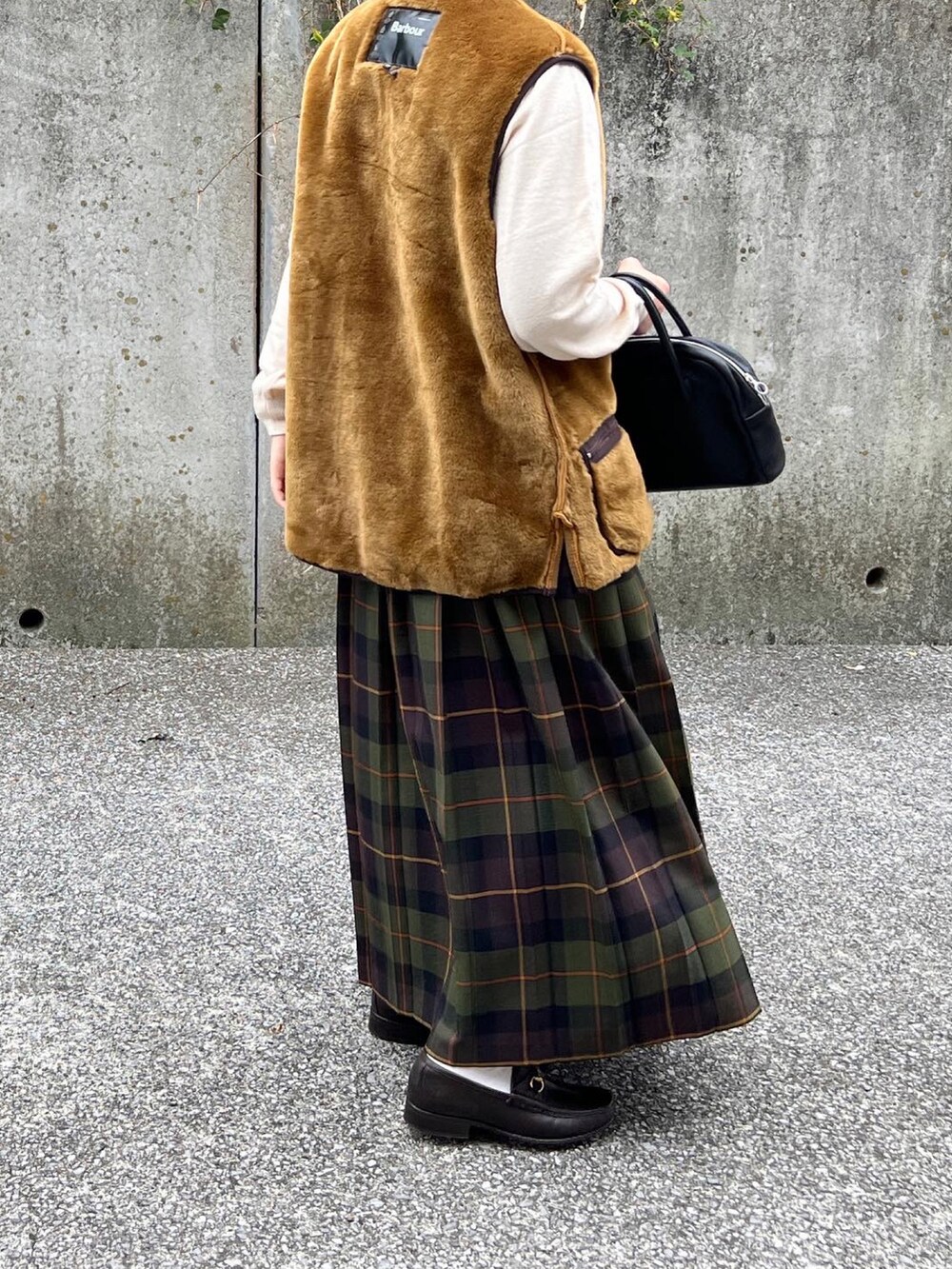 ブラック系のバッグ、ホワイト系のニット/セーター、ブラウン系のベストを着用したレディースの秋コーディネートの2枚目の写真