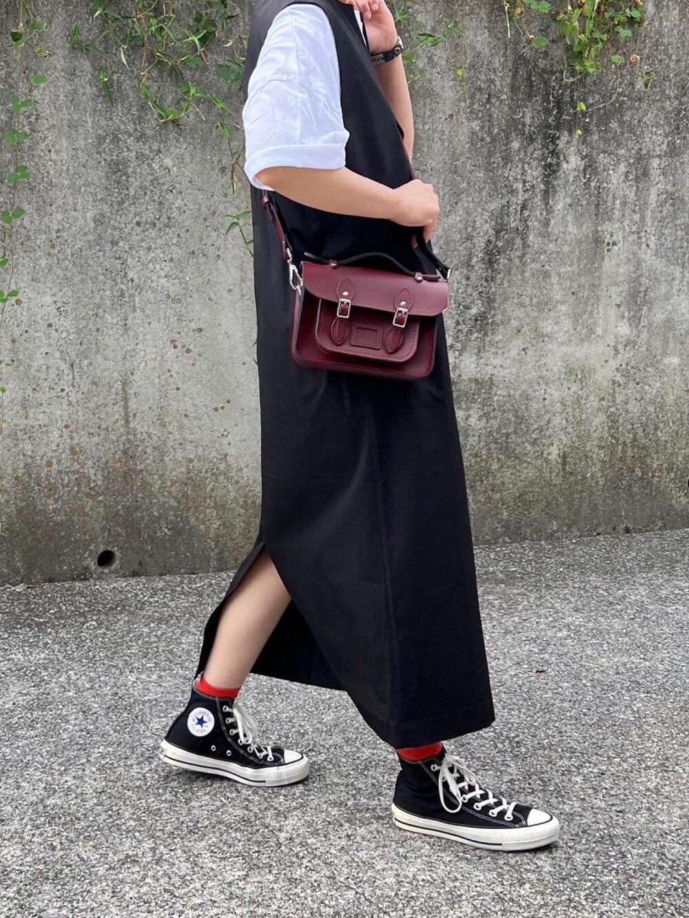 ブラウン系のショルダーバッグ、ブラック系のジャンパースカート、ブラック系のスニーカーを着用したレディースの秋コーディネートの4枚目の写真