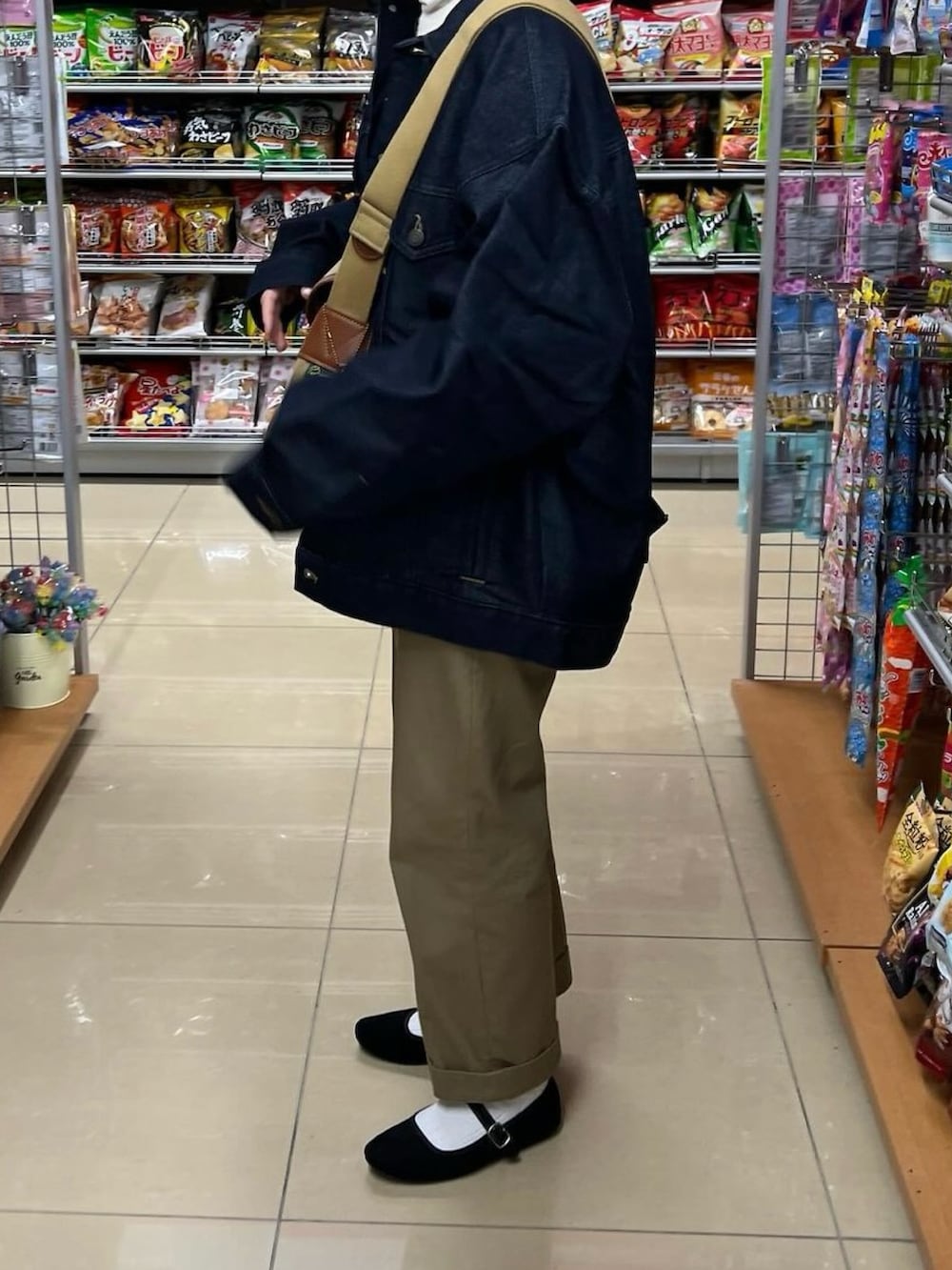 ブルー系のデニムジャケット、グリーン系のショルダーバッグ、ベージュ系のチノパンツを着用したレディースの冬コーディネートの2枚目の写真