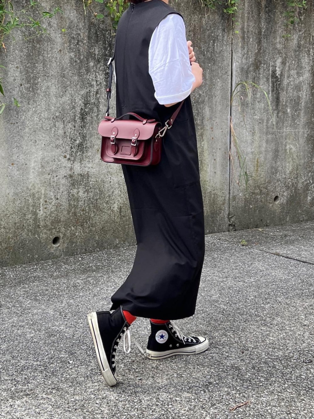 ブラウン系のショルダーバッグ、ブラック系のジャンパースカート、ブラック系のスニーカーを着用したレディースの秋コーディネートの2枚目の写真