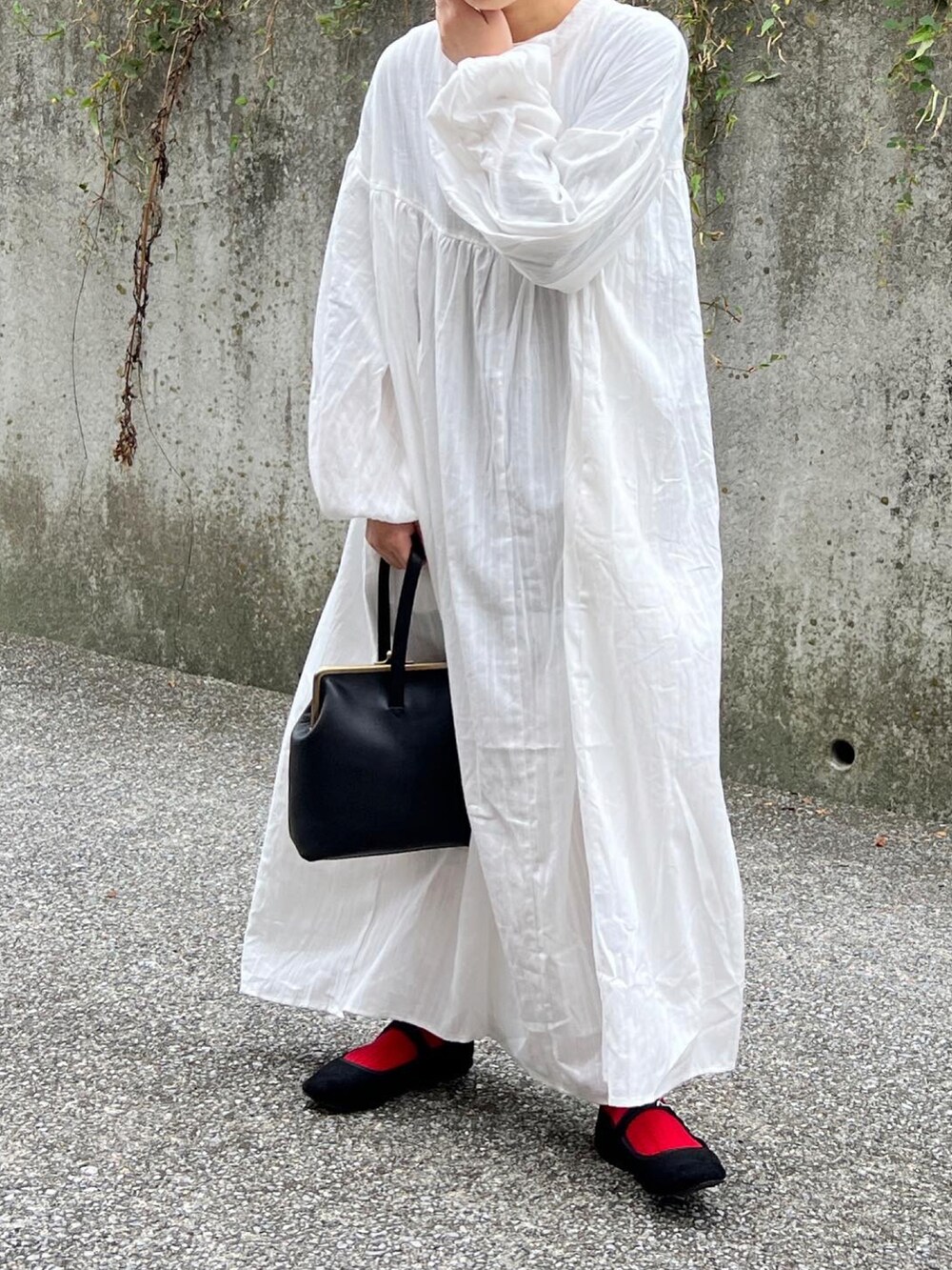 ブラック系のノーカラーコート、ホワイト系のワンピースを着用したレディースの秋コーディネートの4枚目の写真