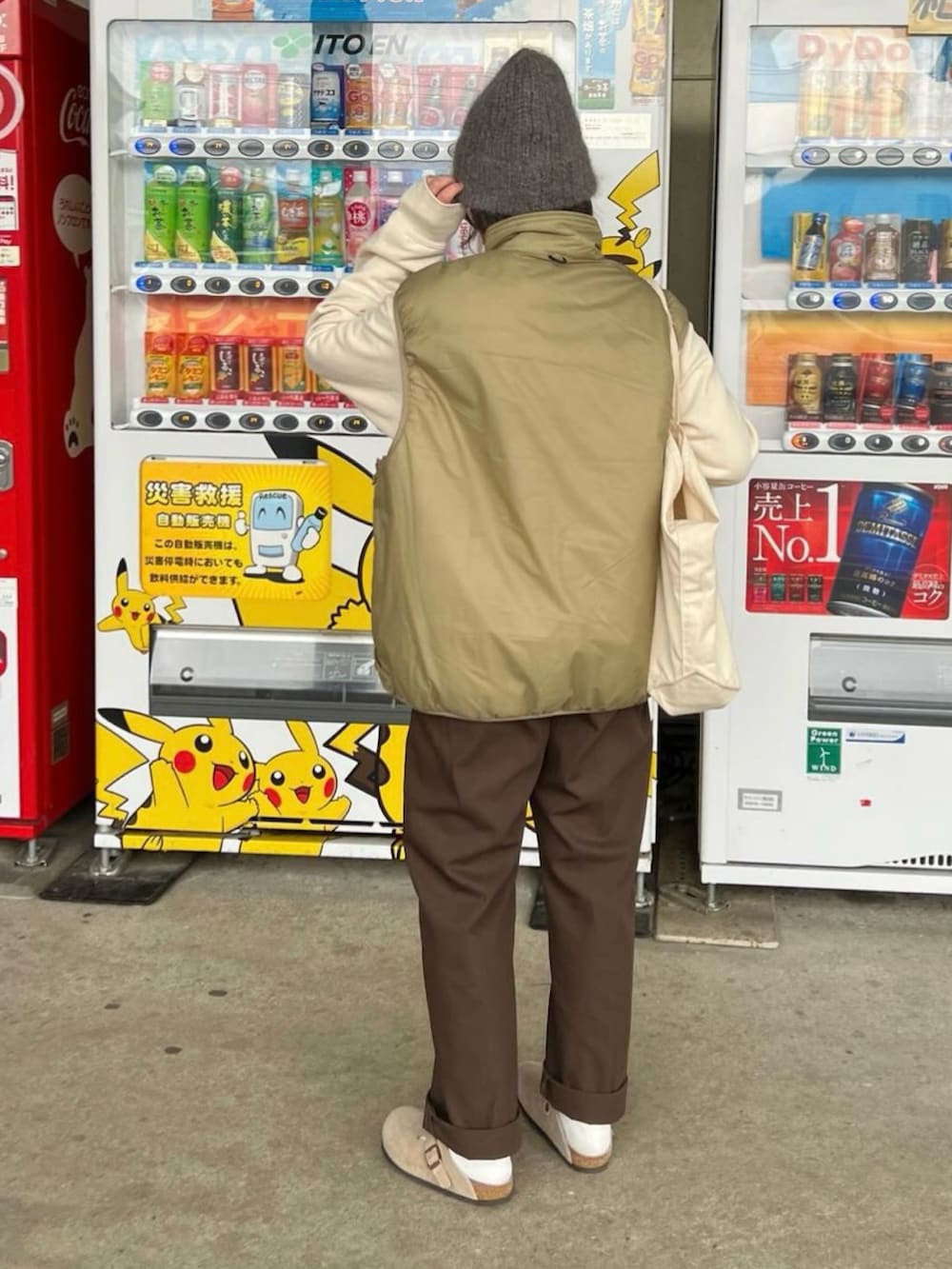 ベージュ系のベスト、ブラウン系のチノパンツ、ベージュ系のサンダルを着用したレディースの冬コーディネートの2枚目の写真