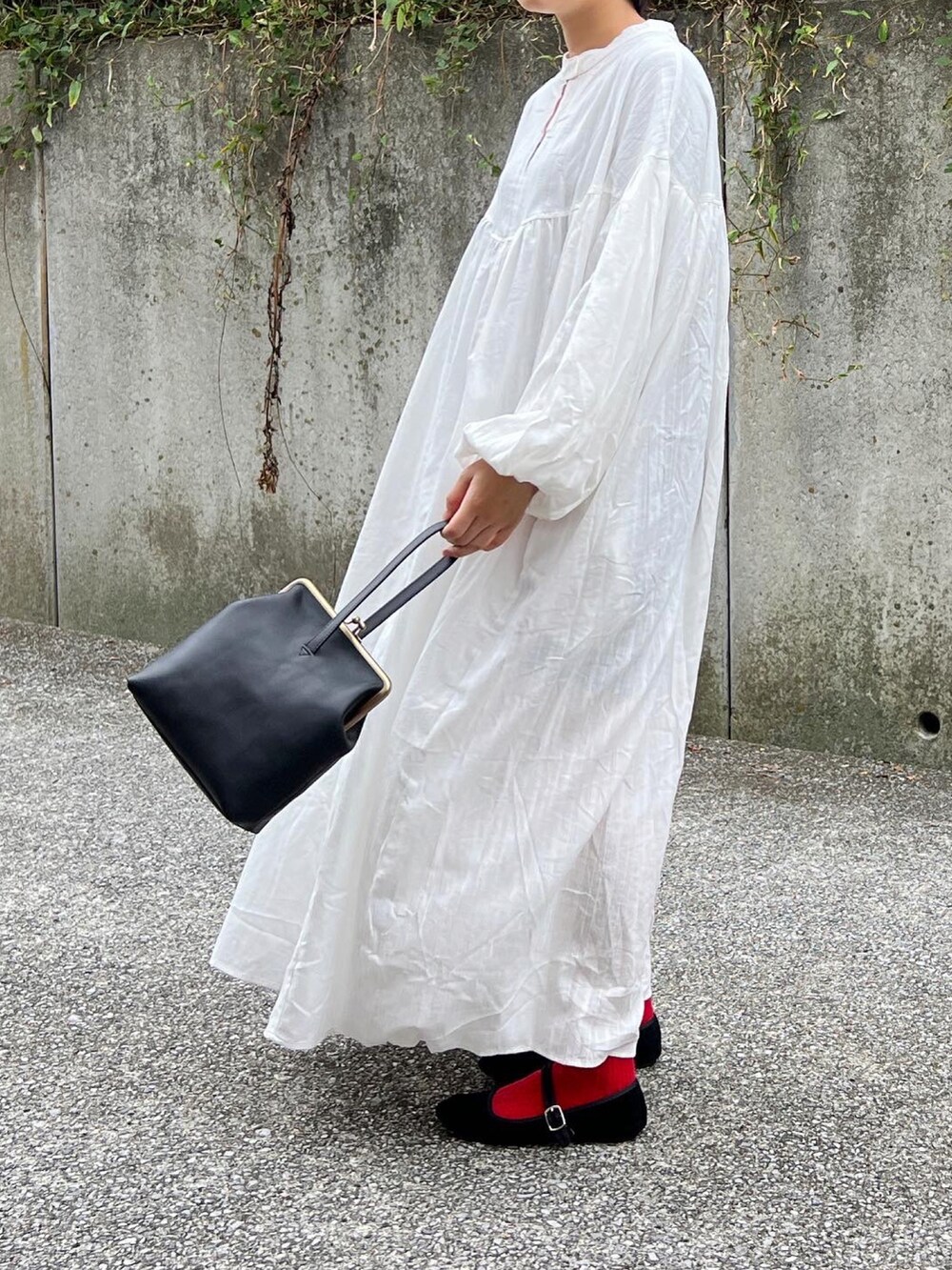 ブラック系のノーカラーコート、ホワイト系のワンピースを着用したレディースの秋コーディネートの3枚目の写真