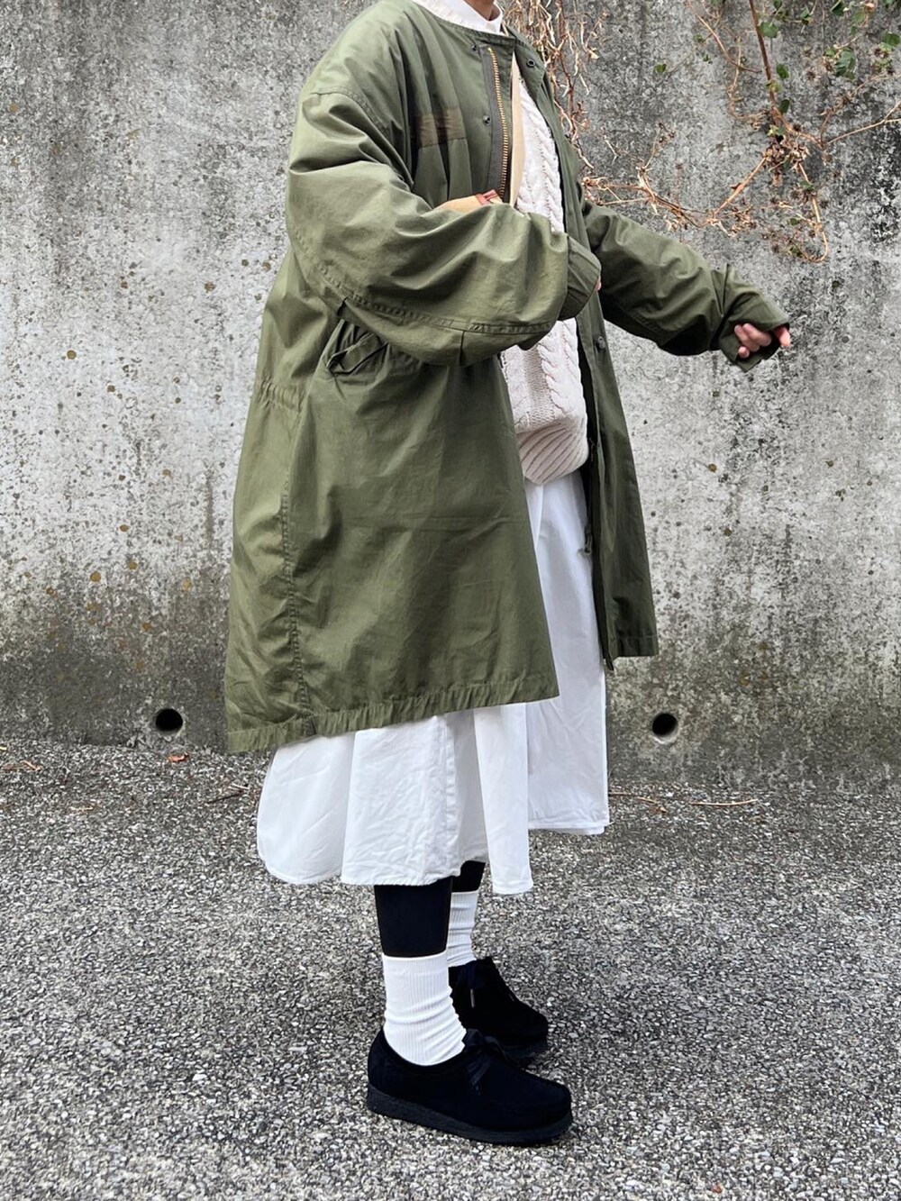 グリーン系のミリタリージャケット、ホワイト系のニット/セーター、ベージュ系のショルダーバッグを着用したレディースの冬コーディネートの2枚目の写真