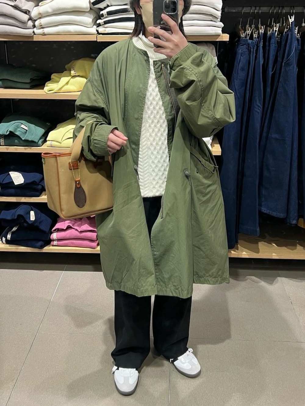 グリーン系のトートバッグ、ホワイト系のスニーカーを着用したレディースの冬コーディネートの2枚目の写真