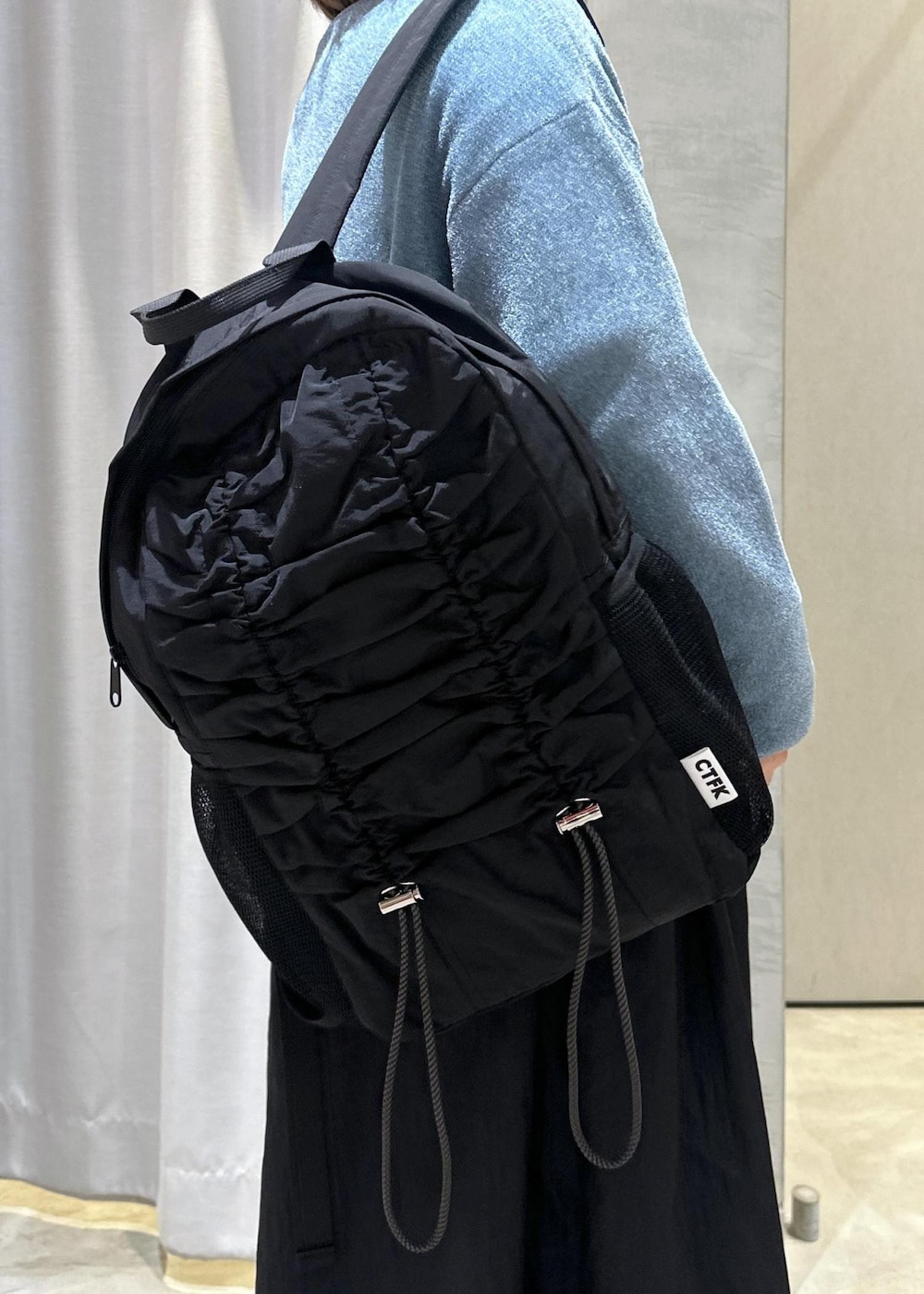 ブラック系のバックパック/リュック、ブラック系のワンピース、ブルー系のカーディガン/ボレロを着用したレディースの秋コーディネートの6枚目の写真