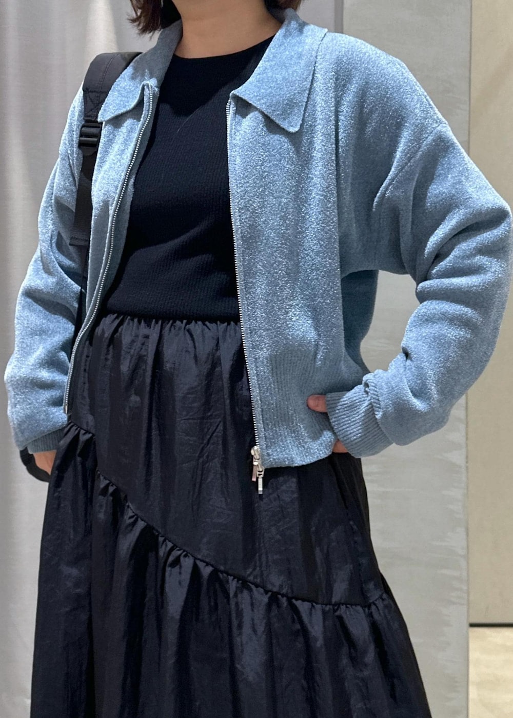 ブラック系のバックパック/リュック、ブラック系のワンピース、ブルー系のカーディガン/ボレロを着用したレディースの秋コーディネートの5枚目の写真