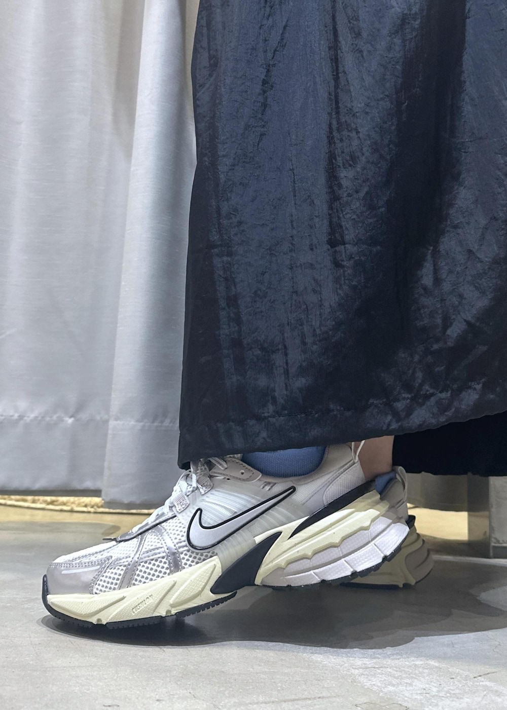 ホワイト系のスニーカー、ホワイト系のショルダーバッグ、ブラック系のワンピースを着用したレディースの秋コーディネートの9枚目の写真