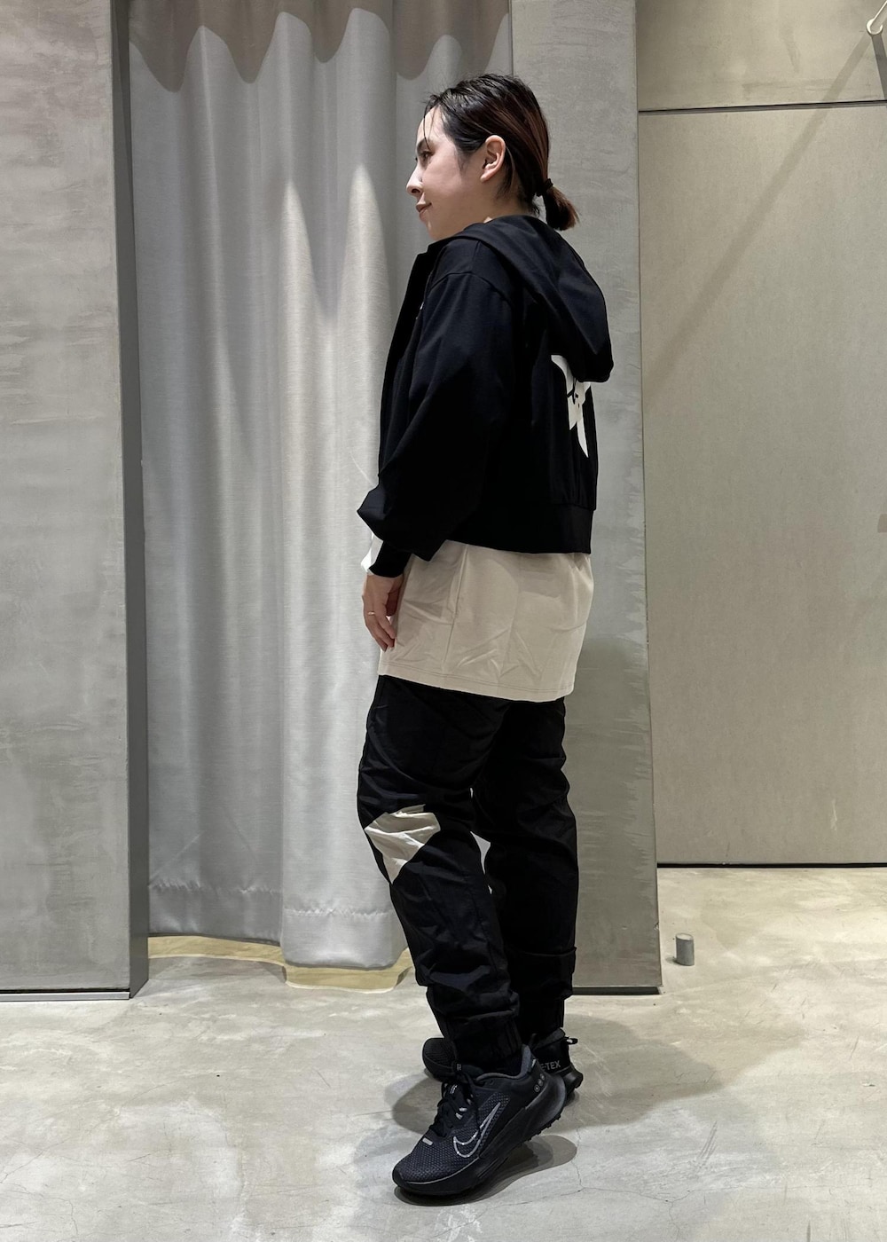 ブラック系のパーカー、ベージュ系のTシャツ/カットソー、ブラック系のスニーカーを着用したレディースの冬コーディネートの2枚目の写真