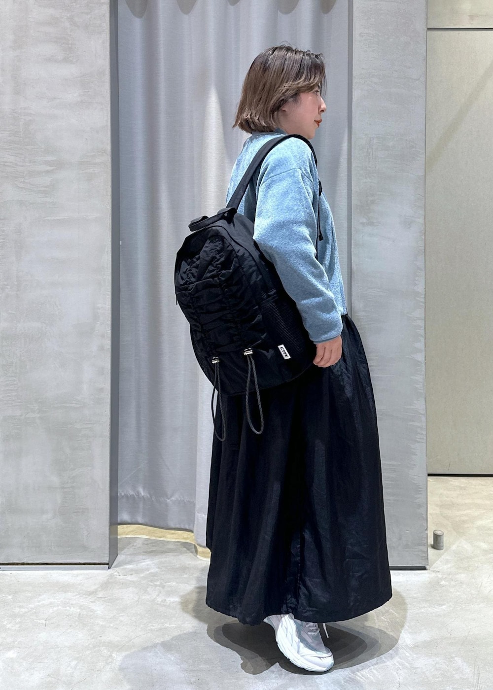 ブラック系のバックパック/リュック、ブラック系のワンピース、ブルー系のカーディガン/ボレロを着用したレディースの秋コーディネートの2枚目の写真