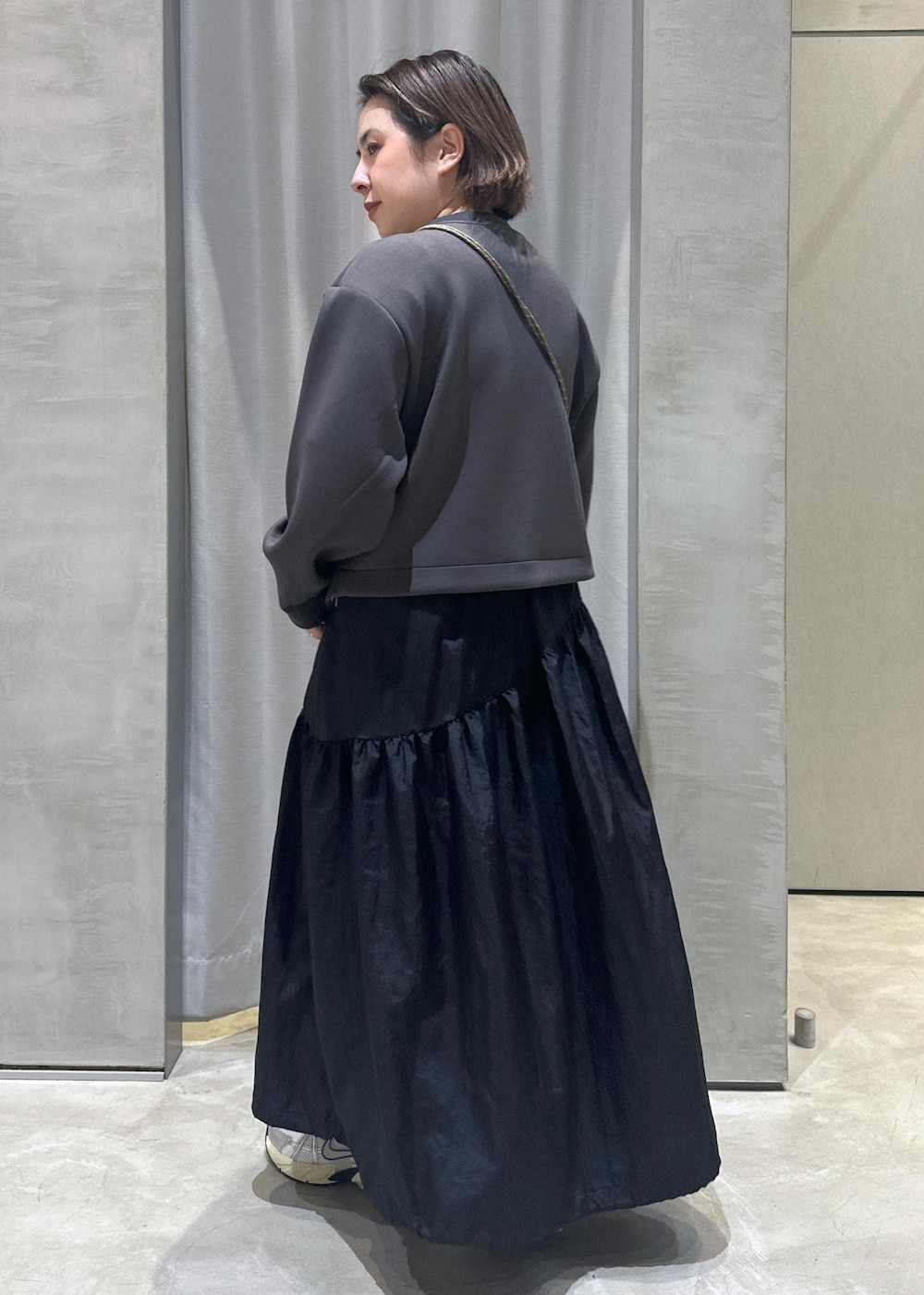 ホワイト系のスニーカー、ホワイト系のショルダーバッグ、ブラック系のワンピースを着用したレディースの秋コーディネートの2枚目の写真