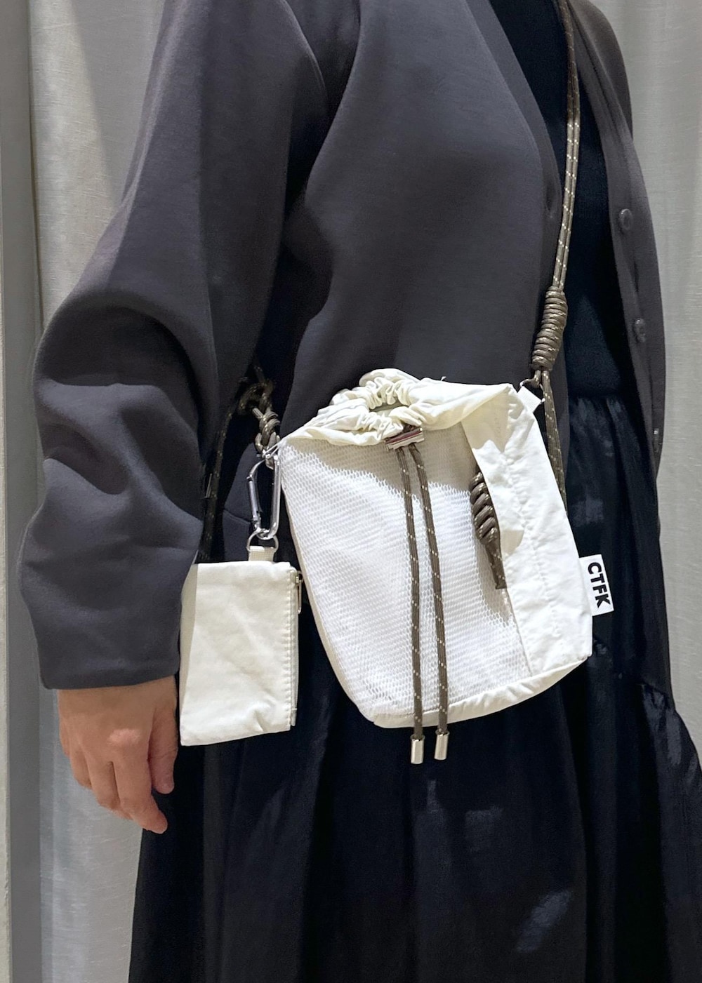 ホワイト系のスニーカー、ホワイト系のショルダーバッグ、ブラック系のワンピースを着用したレディースの秋コーディネートの6枚目の写真