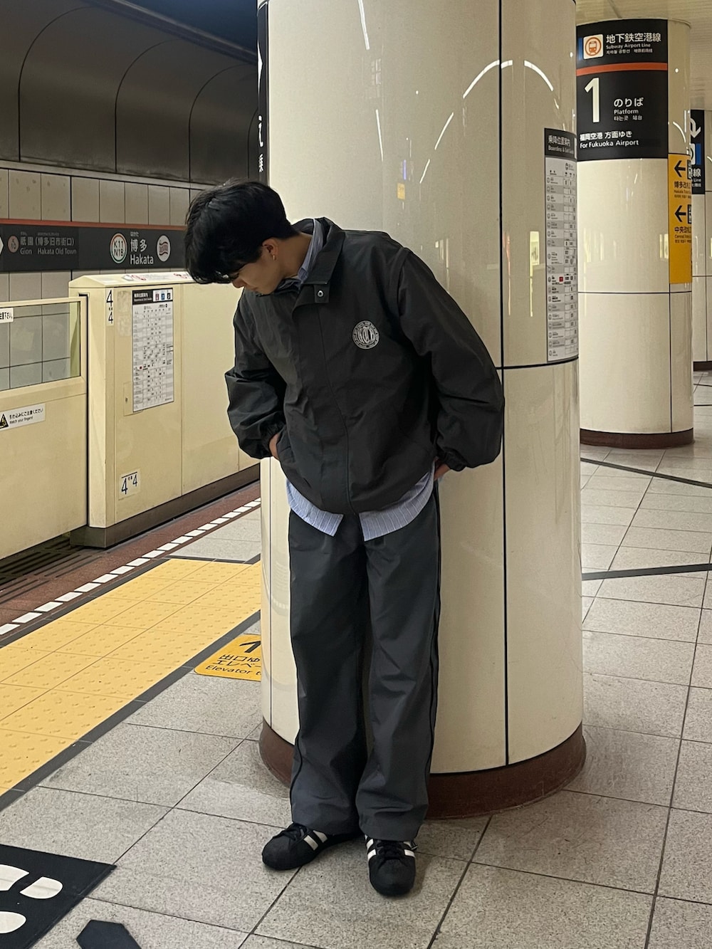 グレー系のブルゾン、グレー系のパンツ、ブラック系のスニーカーを着用したメンズの春コーディネートの2枚目の写真
