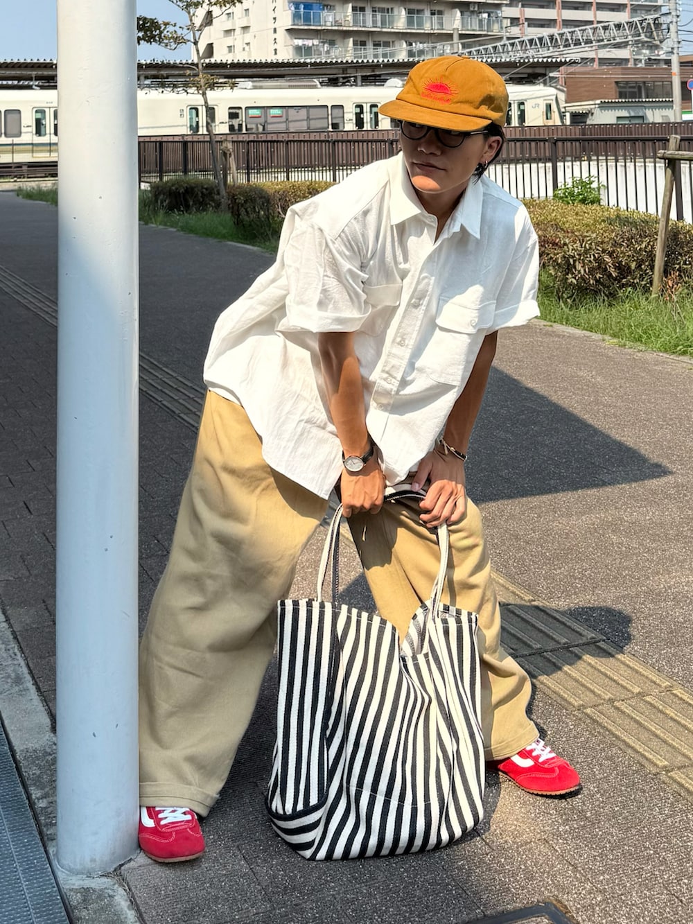 ベージュ系のチノパンツ、レッド系のスニーカー、ホワイト系のシャツ/ブラウスを着用したメンズの夏コーディネートの3枚目の写真