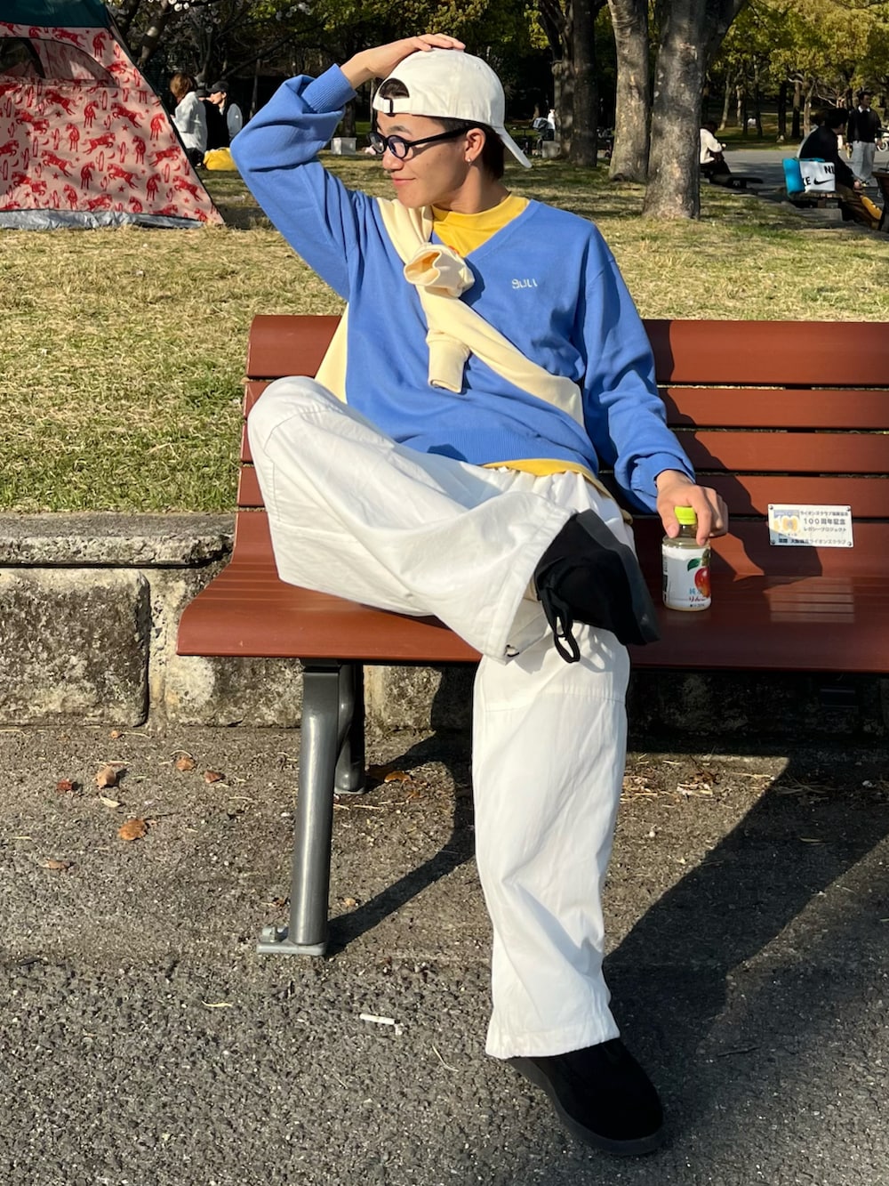 ブラック系のモカシン/デッキシューズ、ホワイト系のパンツ、ブルー系のニット/セーターを着用したメンズの春コーディネートの2枚目の写真