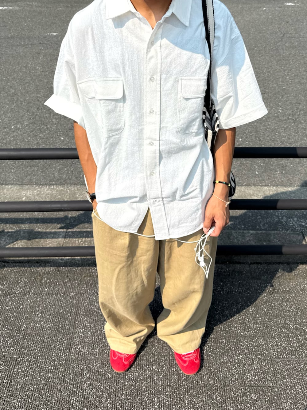 ベージュ系のチノパンツ、レッド系のスニーカー、ホワイト系のシャツ/ブラウスを着用したメンズの夏コーディネートの4枚目の写真