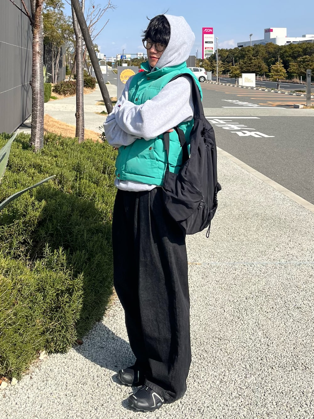 ブラック系のデニムパンツ、ブラック系のスニーカー、ブルー系のベストを着用したメンズの冬コーディネートの2枚目の写真