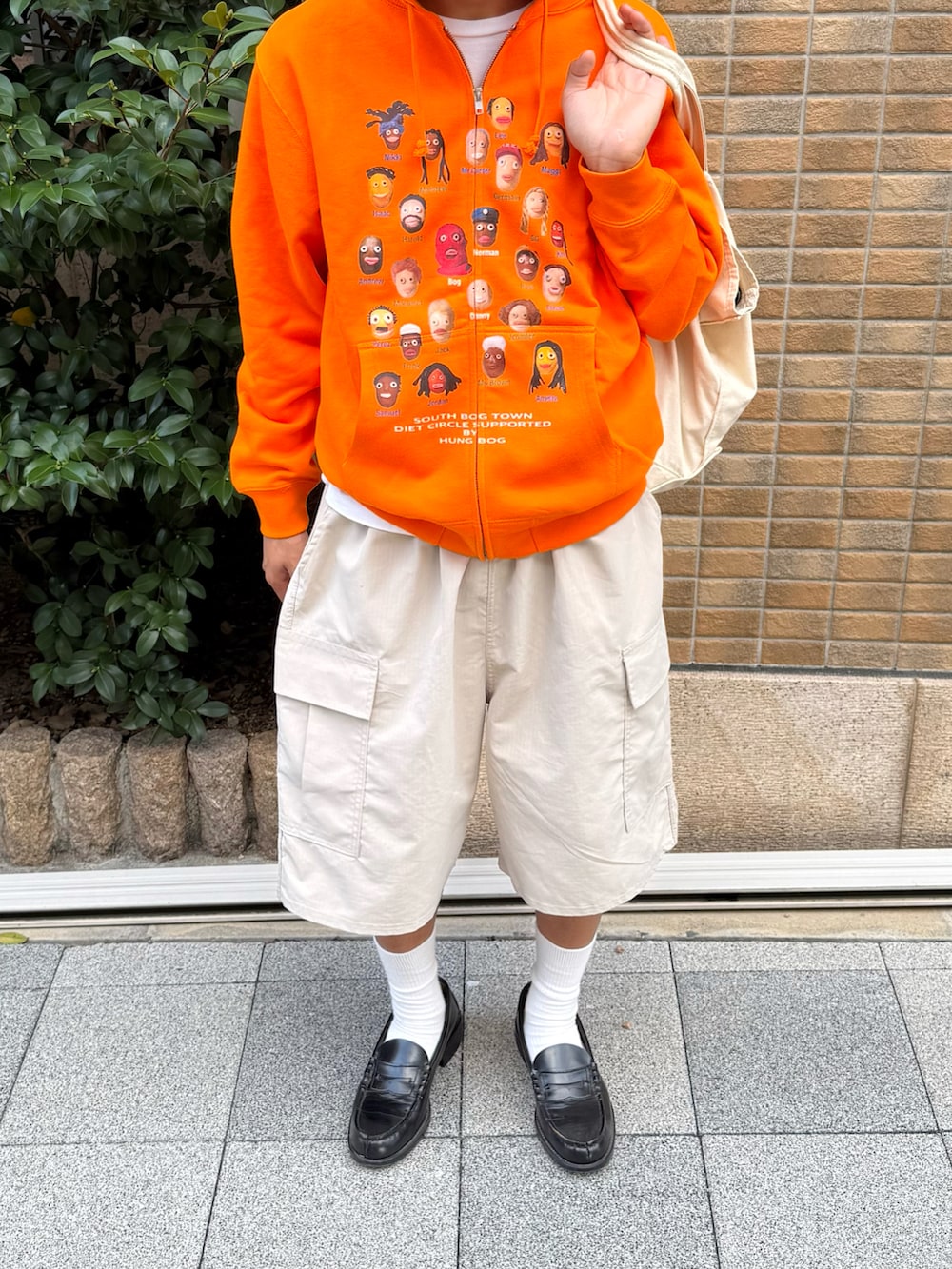 ブラック系のローファー、ホワイト系のトートバッグ、オレンジ系のパーカーを着用したメンズの秋コーディネートの2枚目の写真